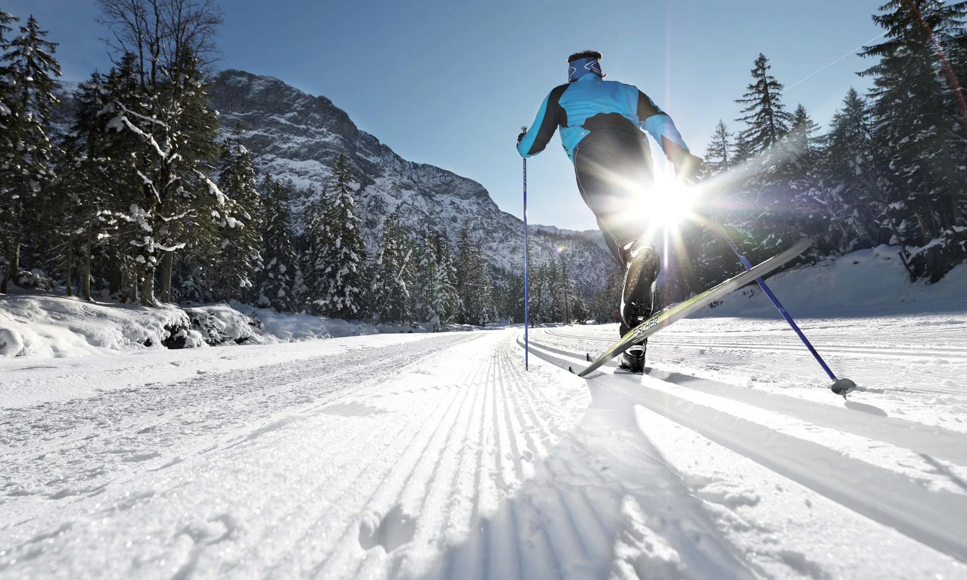 Your unforgettable active lakeside holiday in Austria Cross-country skier gliding on snowy trail with sun shining through trees