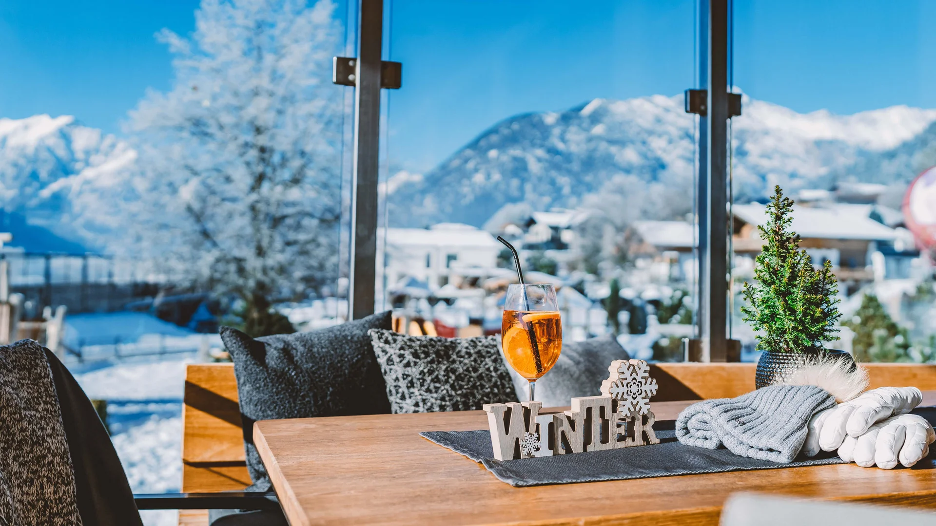 Willkommen im Familienhotel Buchau am Achensee Winterdekoration und Getränk auf Holztisch vor verschneiter Berglandschaft