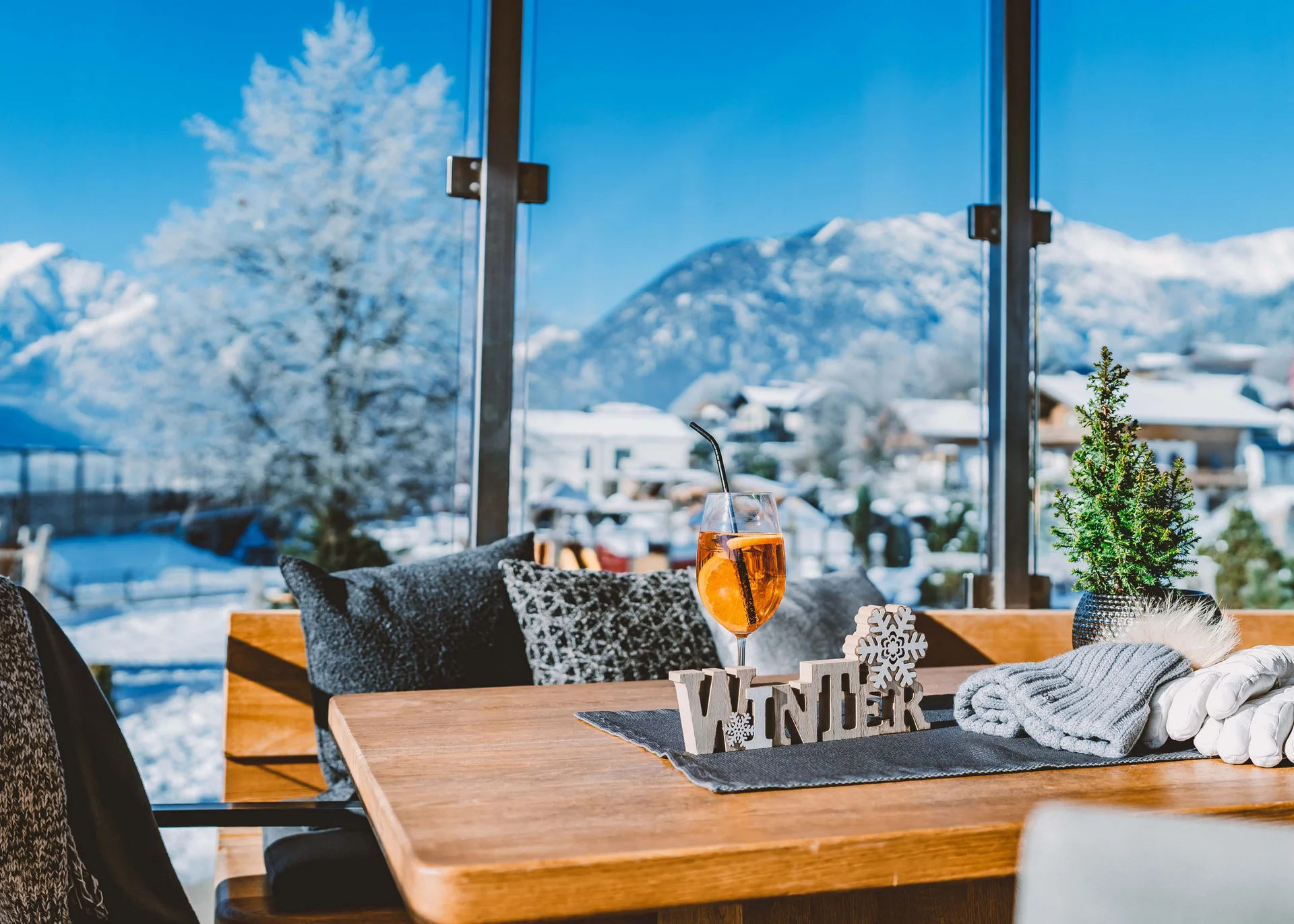 Erholungsurlaub für Eltern Winterdekoration und Getränk auf Holztisch vor verschneiter Berglandschaft