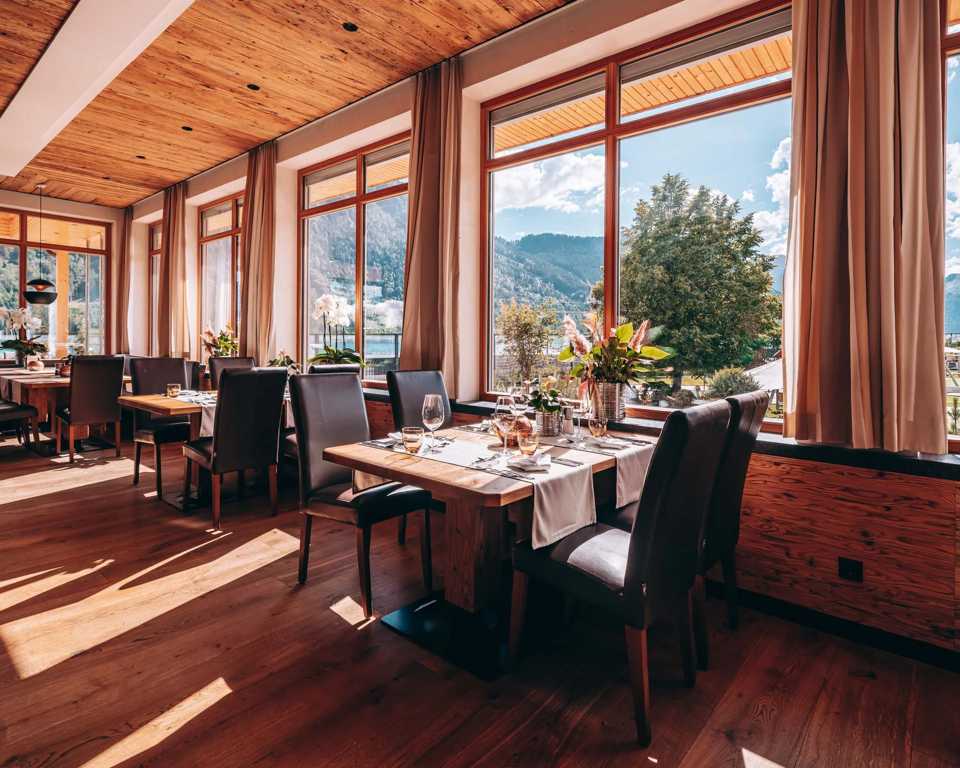 Welcome to our family hotel at Lake Achensee. Bright restaurant with wood floor and large windows overlooking mountains
