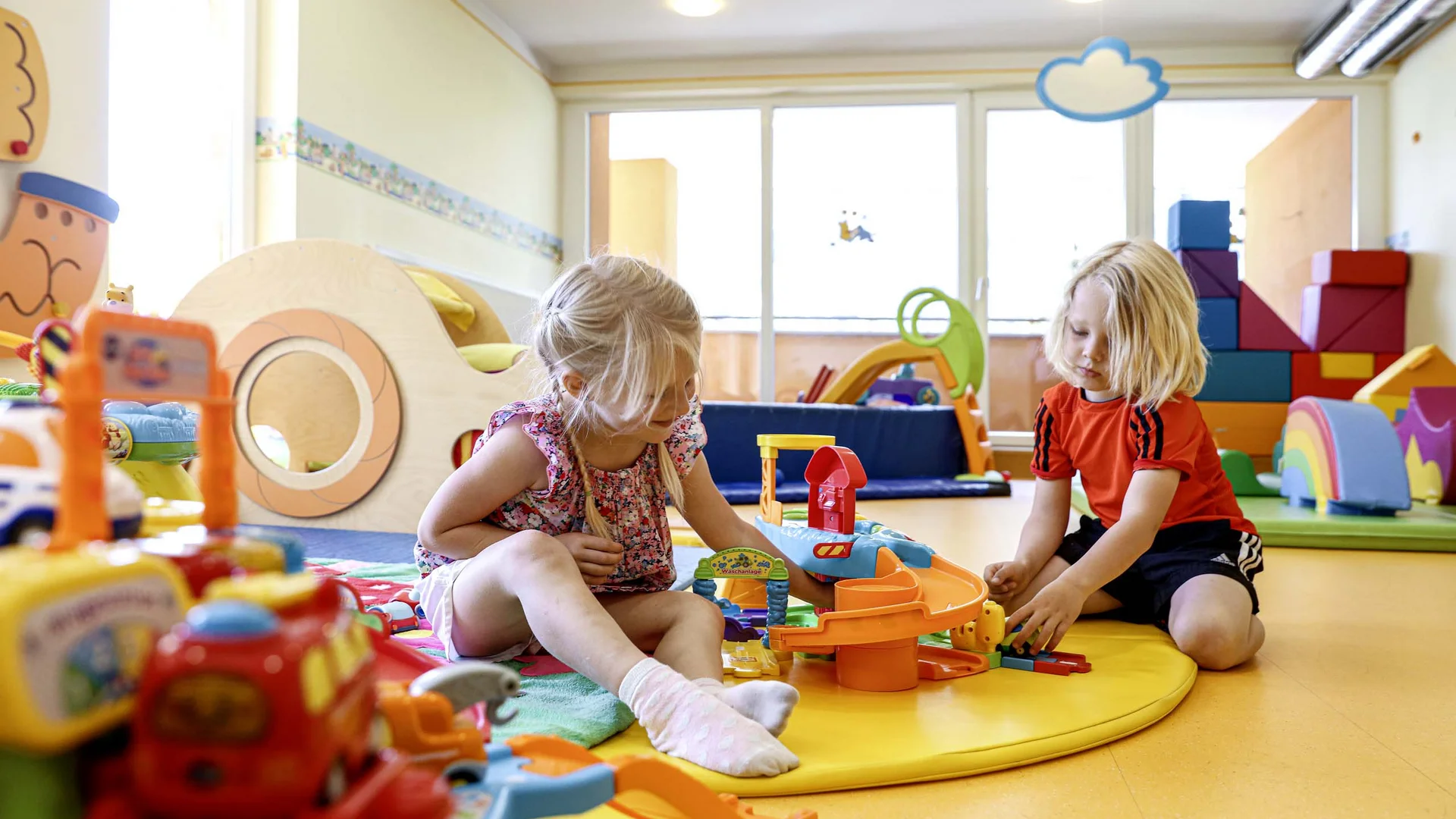 Ihr Hotel mit Kinderbetreuung in Tirol Kinder spielen mit buntem Spielzeug im hellen Spielzimmer