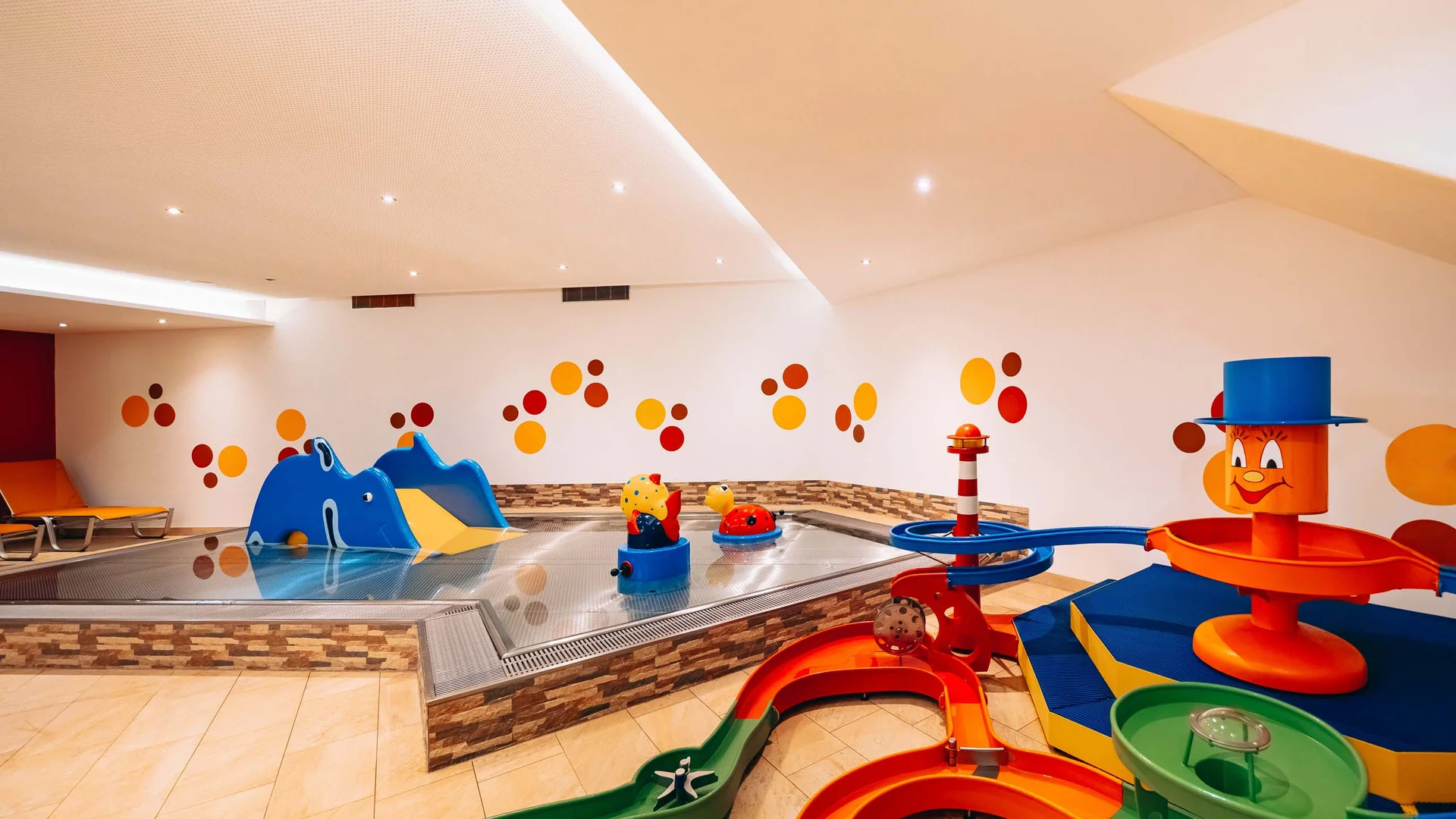 Ihr Hotel mit Kinderbetreuung in Tirol Buntes Indoor-Kinderbecken mit Rutschen und Wasserspielzeug