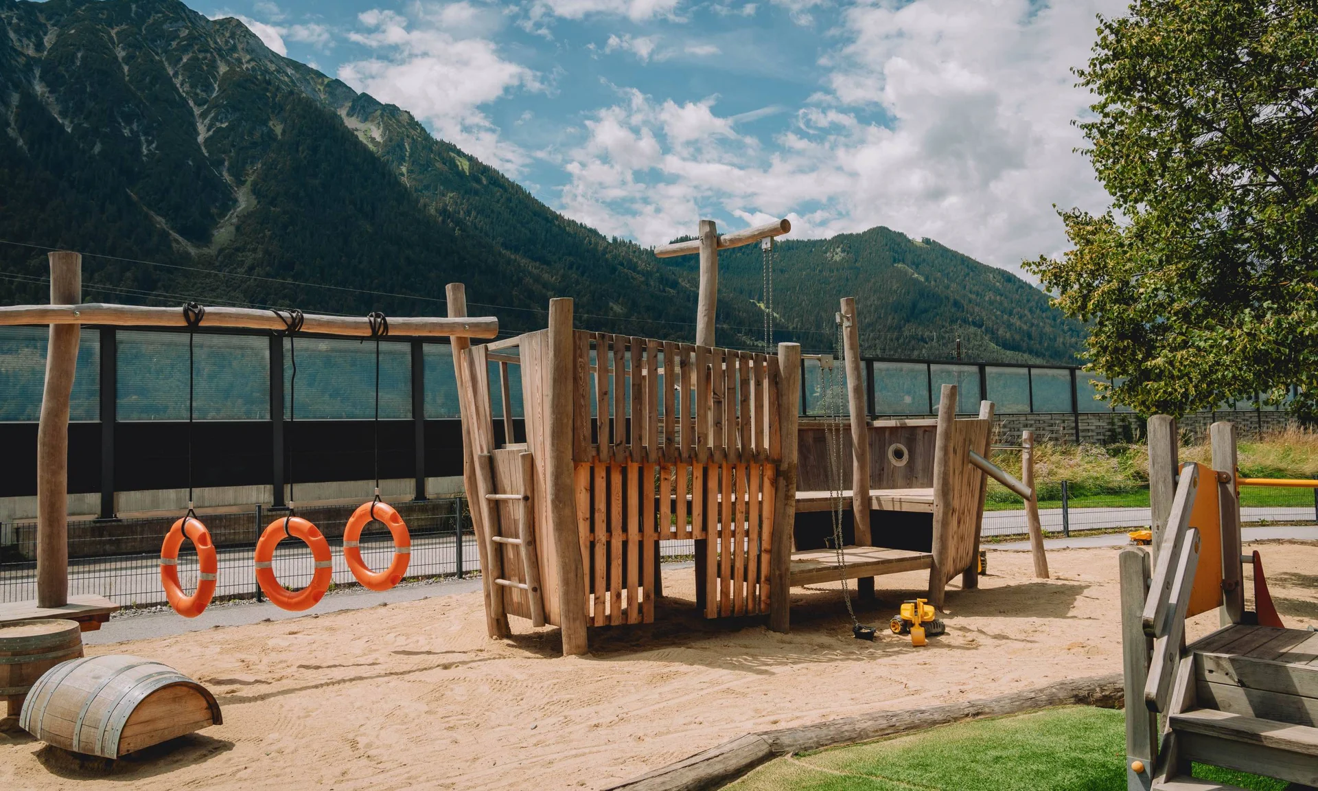 Outdoorspaß im Familienhotel am See in Österreich Kinderspielplatz mit Holzgerüst und Bergen im Hintergrund
