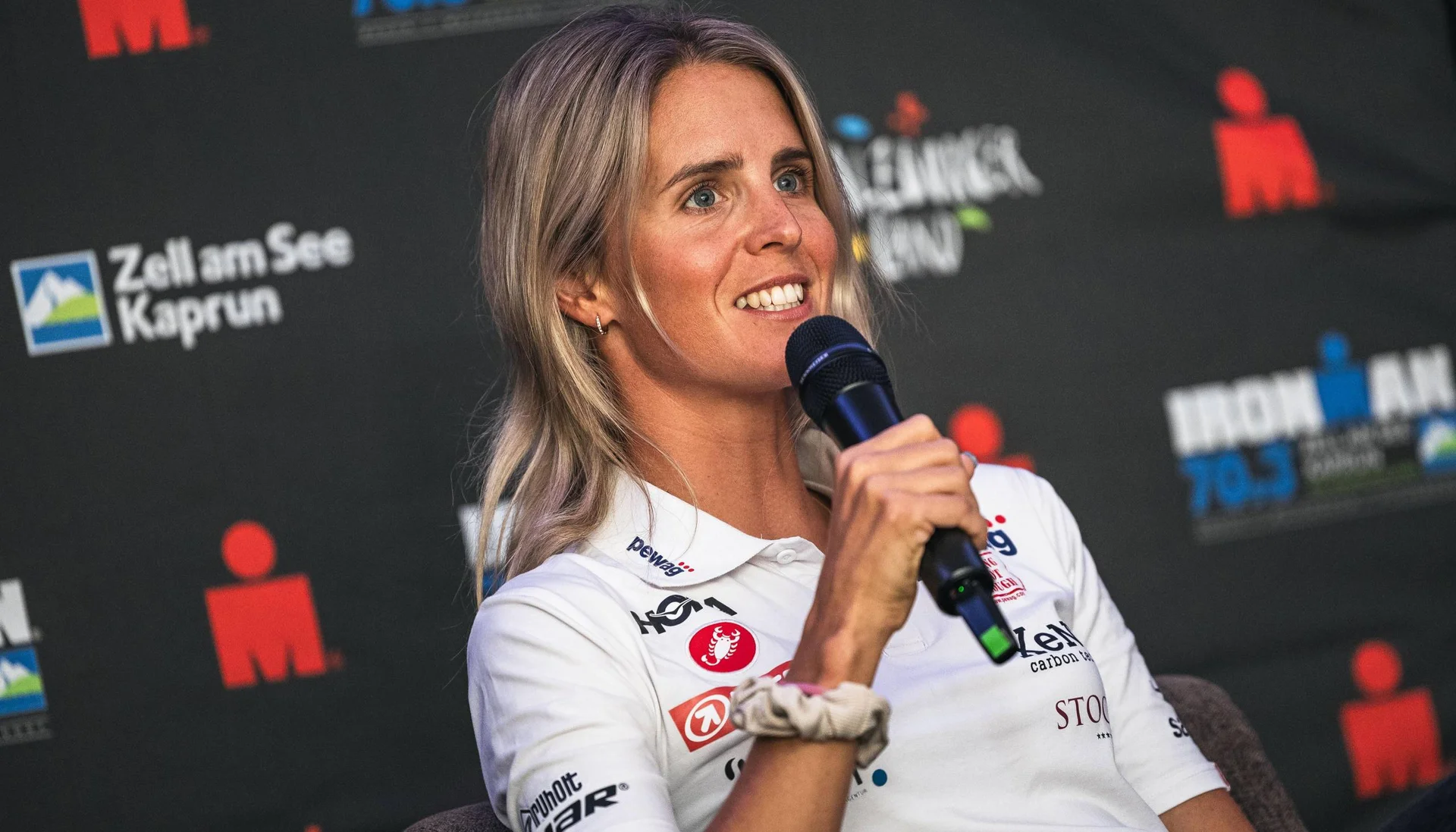 Fitness und Yoga im Hotel in Tirol Frau spricht in Mikrofon vor Ironman-Event-Hintergrund