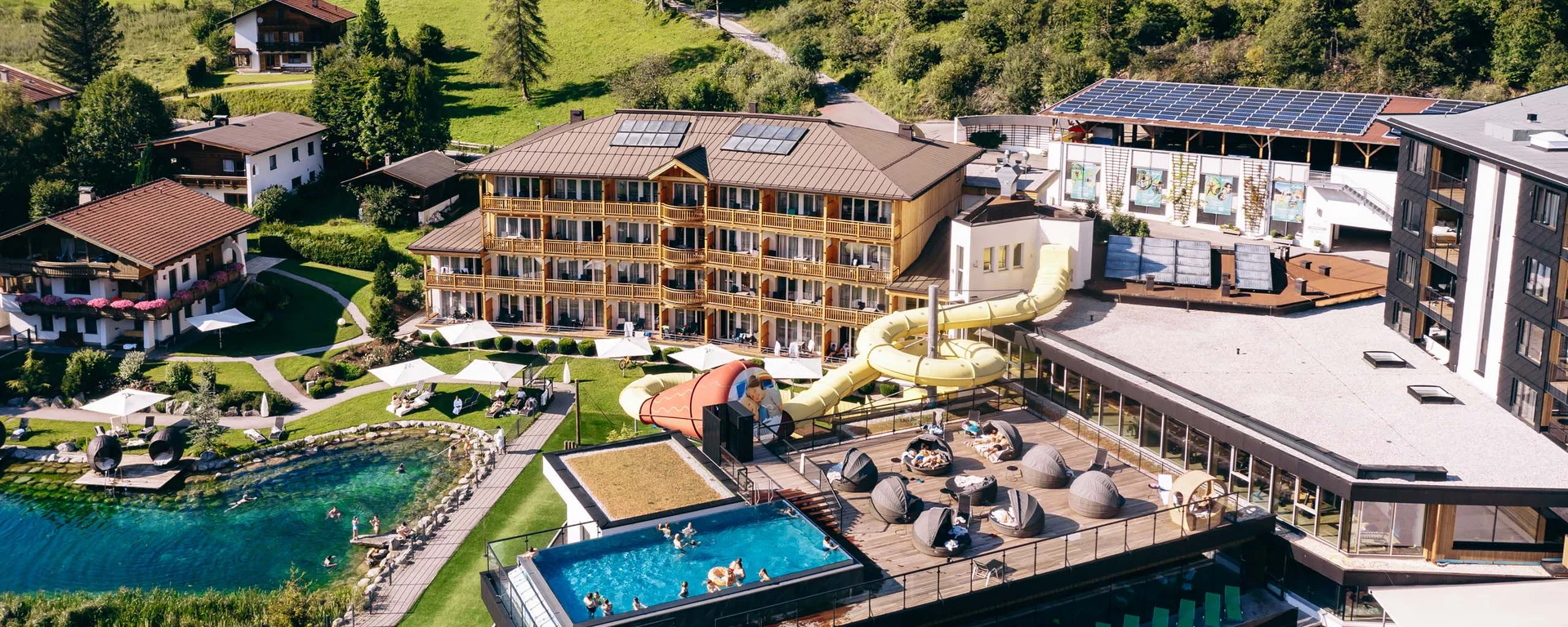 Familienzeit im Kinderhotel Buchau am Achensee Hotelresort mit Außenpool, Wasserrutsche, Badeteich und Liegebereichen in Berglandschaft