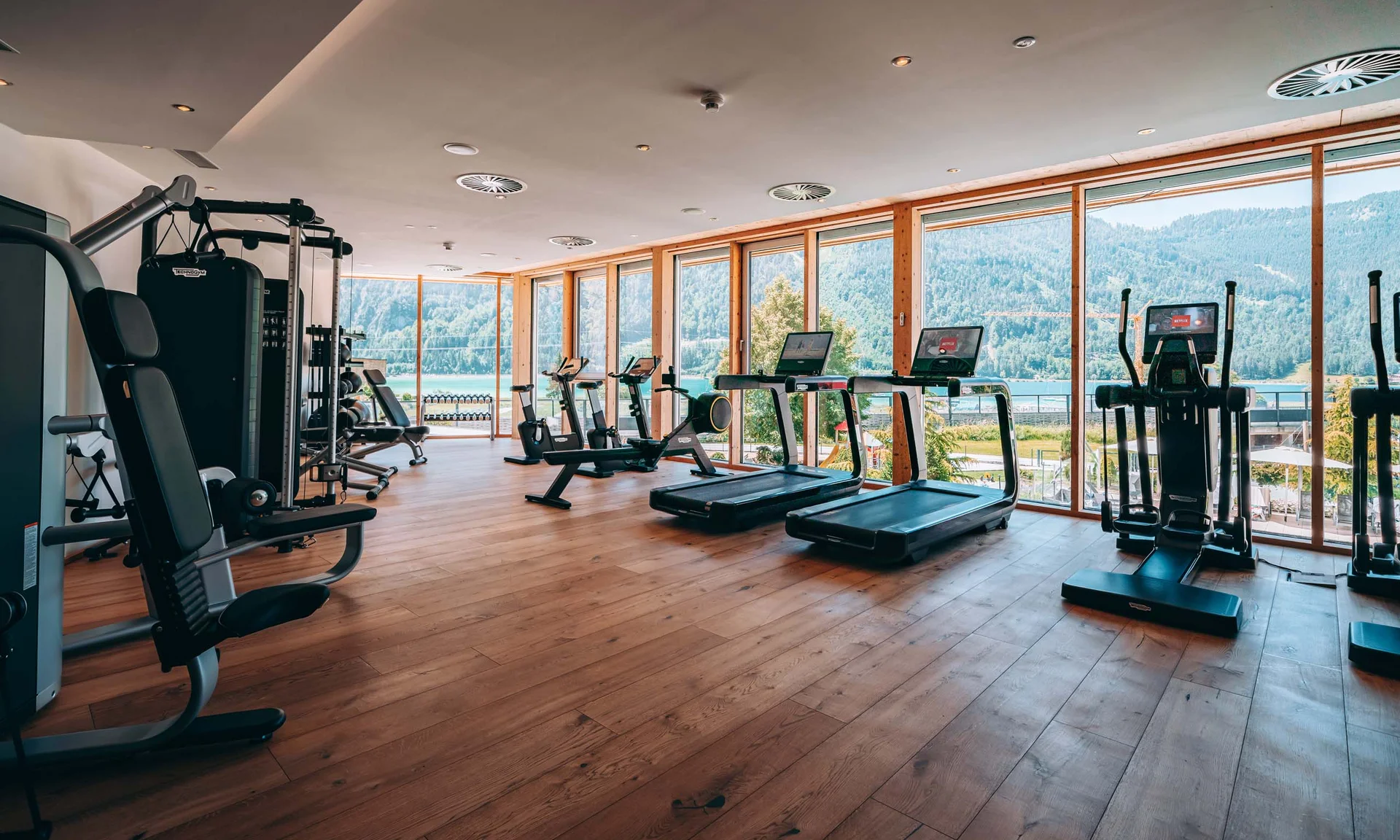 Wir lassen Bilder sprechen. Helles Fitnessstudio mit Geräten und großem Fenster mit Bergblick