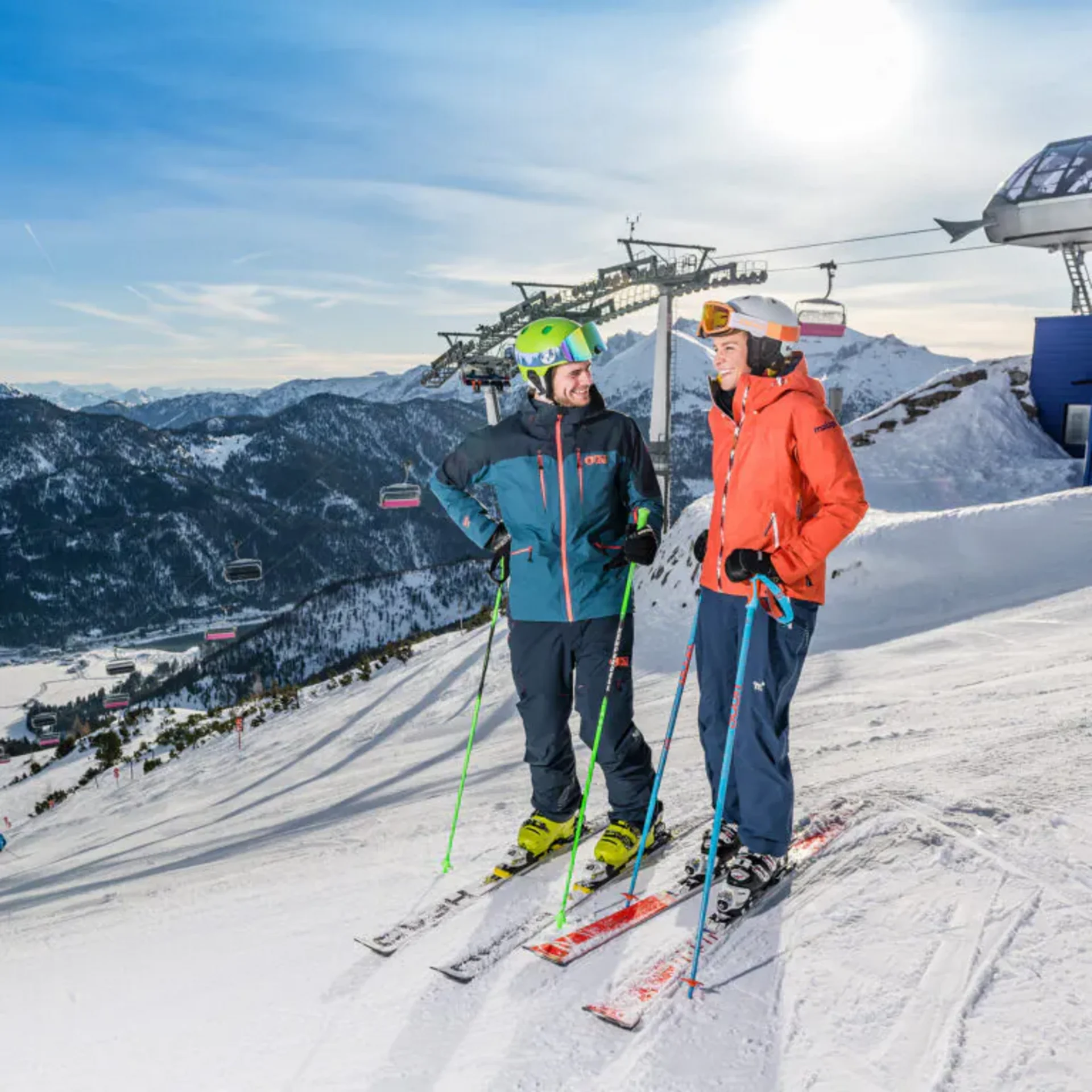 Der Wintertraum im Familien-Skihotel in Österreich Zwei Skifahrer stehen auf verschneiter Piste vor Berglandschaft und Skilift