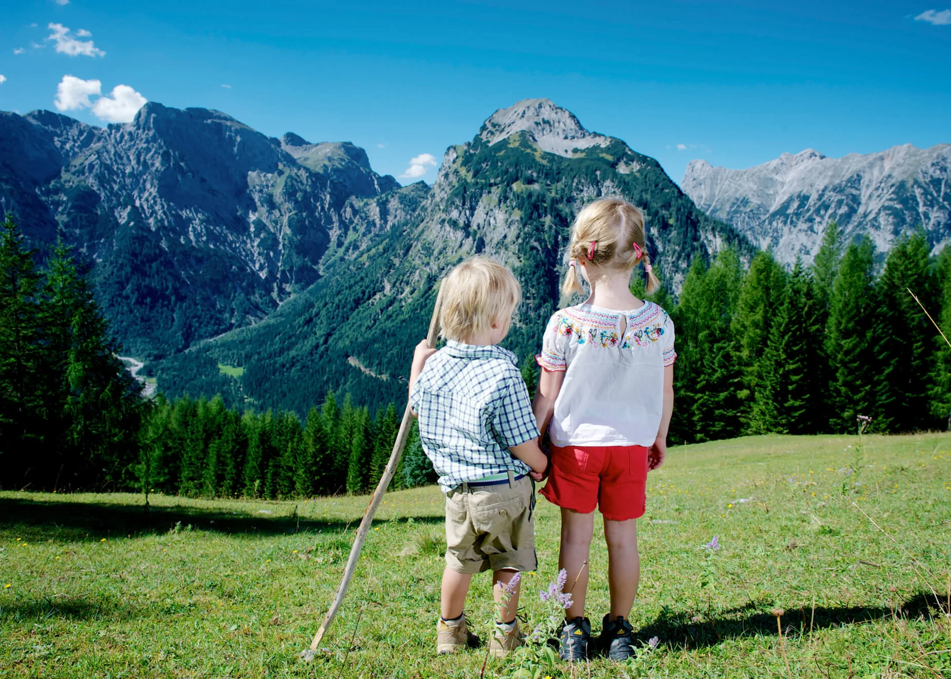 Ihr langersehnter Urlaub mit Enkelkind Kinder in den Alpen blicken auf Berge und Wälder unter blauem Himmel