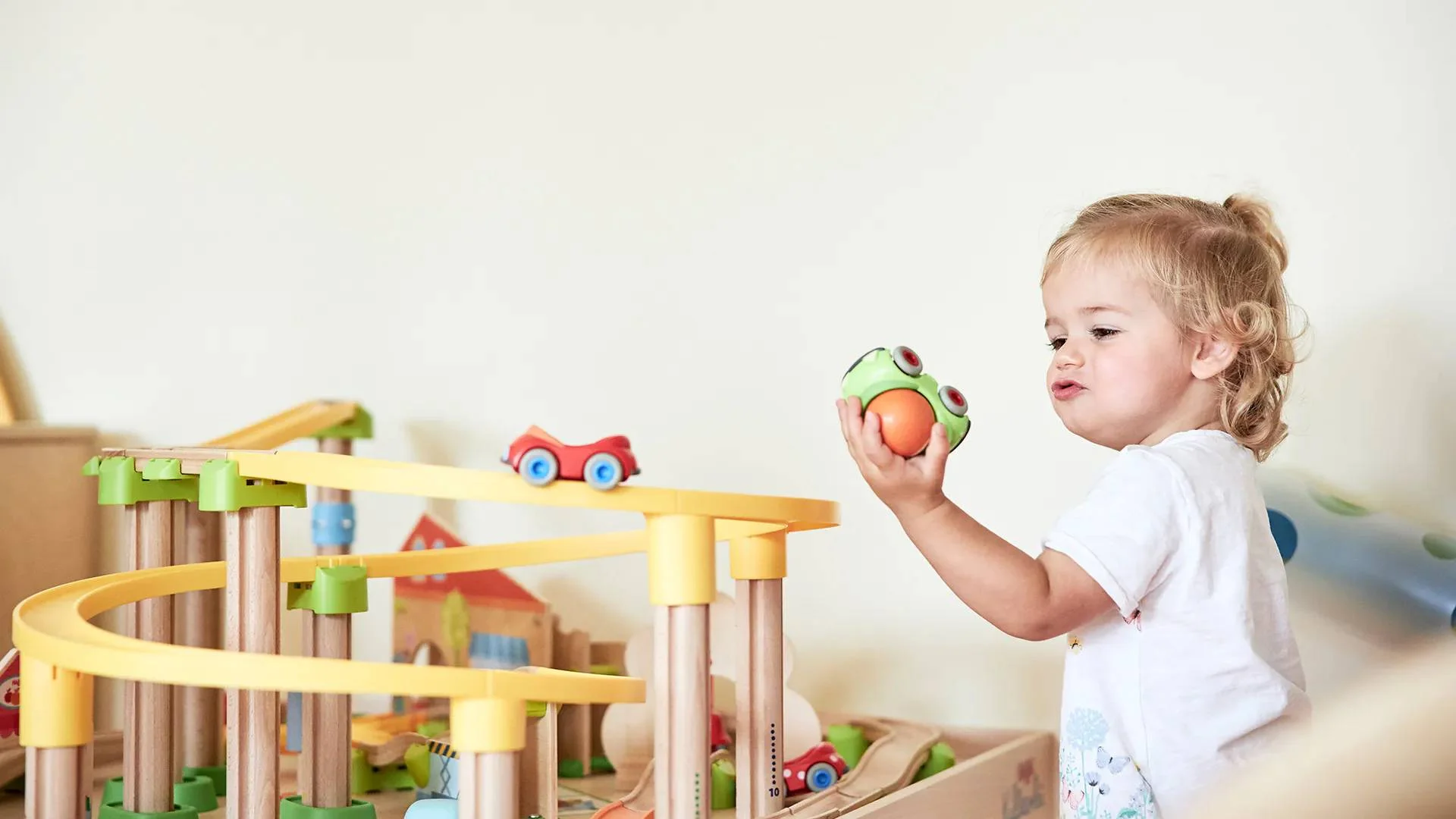 Urlaub im Hotel mit Indoorspielplatz Kleines Kind spielt mit einer Holzeisenbahn und Spielsachen zu Hause.
