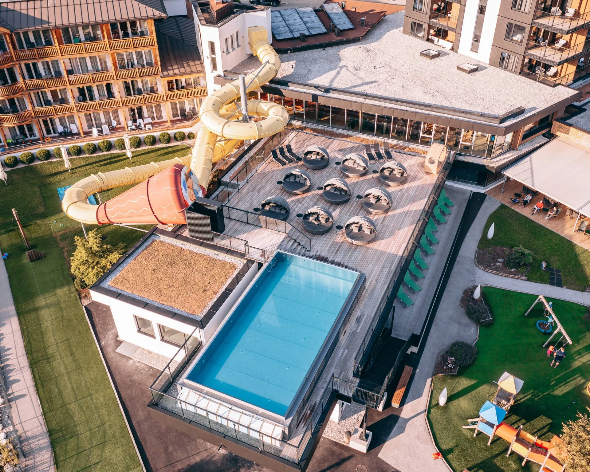 Ab ins Wellnesshotel in Tirol, in den Infinitypool! Dachterrasse mit Pool, Rutsche und Außenbereich eines Hotels