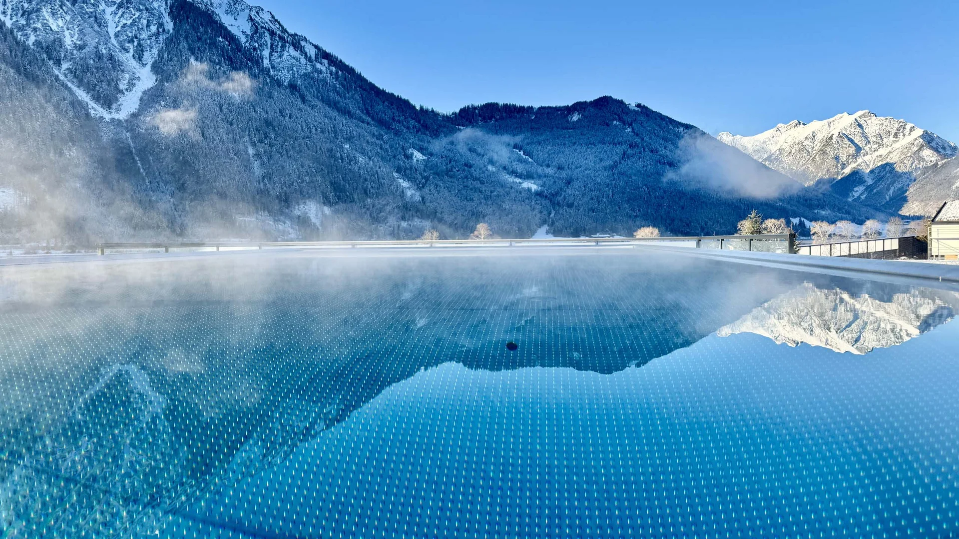 Wasserspaß im Familienhotel in Tirol mit Pool Dampfender Pool mit Spiegelung schneebedeckter Berge im Hintergrund