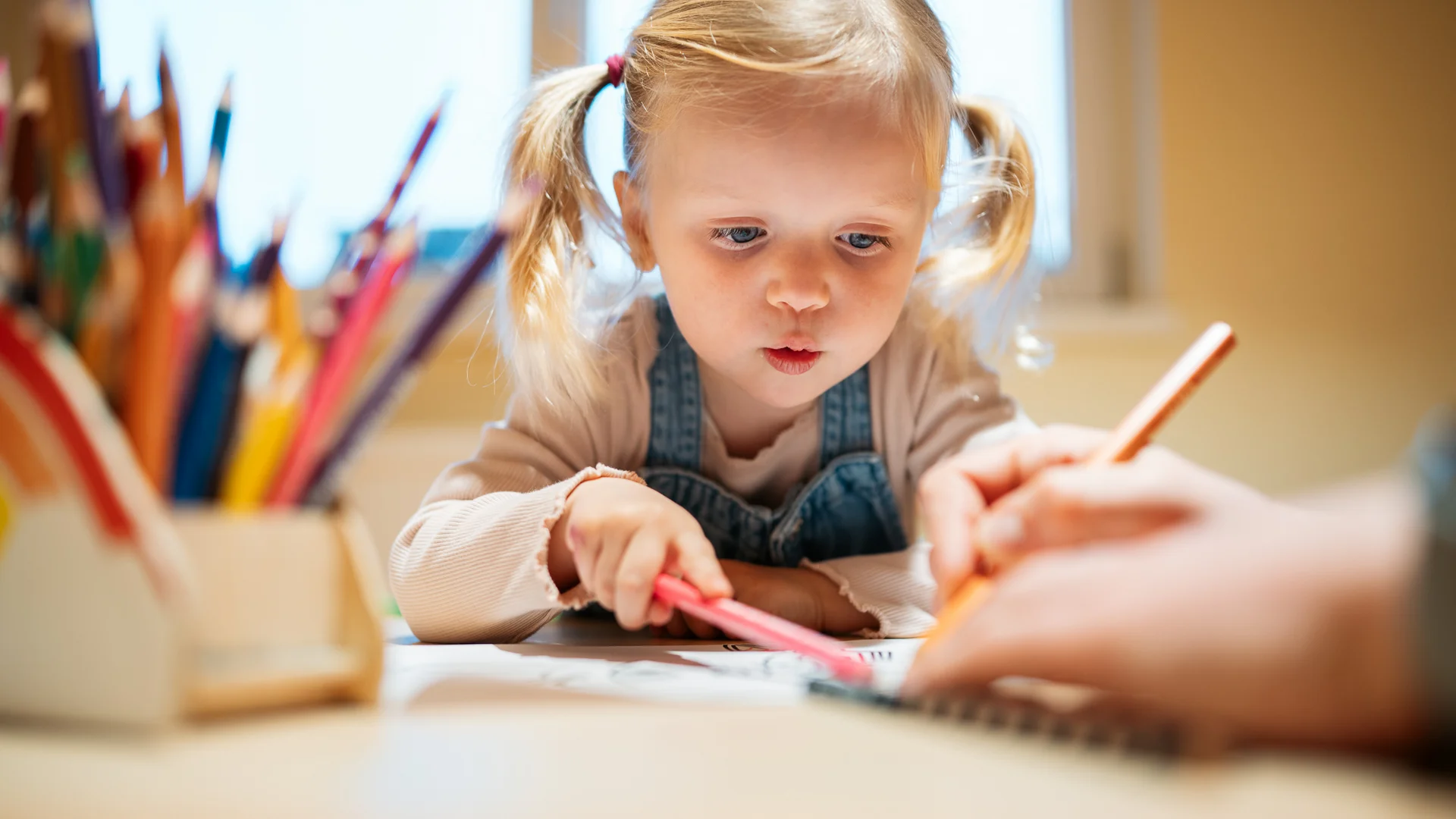 Ihr Familienhotel in Österreich mit All-inclusive-Angebot Kleines Mädchen malt konzentriert mit Buntstiften an einem Tisch