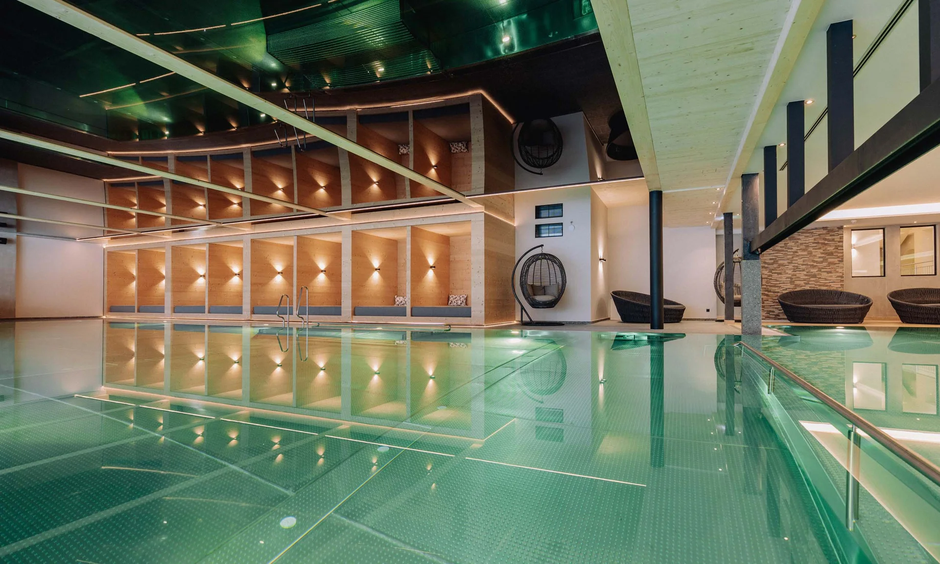 Urlaub im Hotel mit Indoorspielplatz Modernes Hallenbad mit Holzdekor und Sitzbereichen neben dem Pool