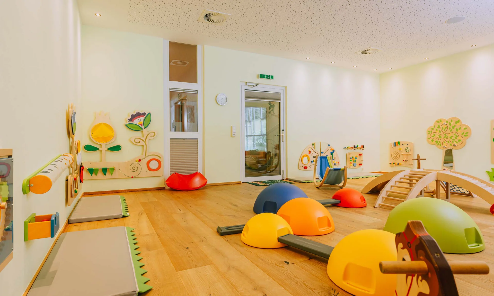 Familienurlaub mit Baby und Kleinkind im Buchau Kinderspielzimmer mit bunten Spielgeräten und Holzspielzeug an der Wand
