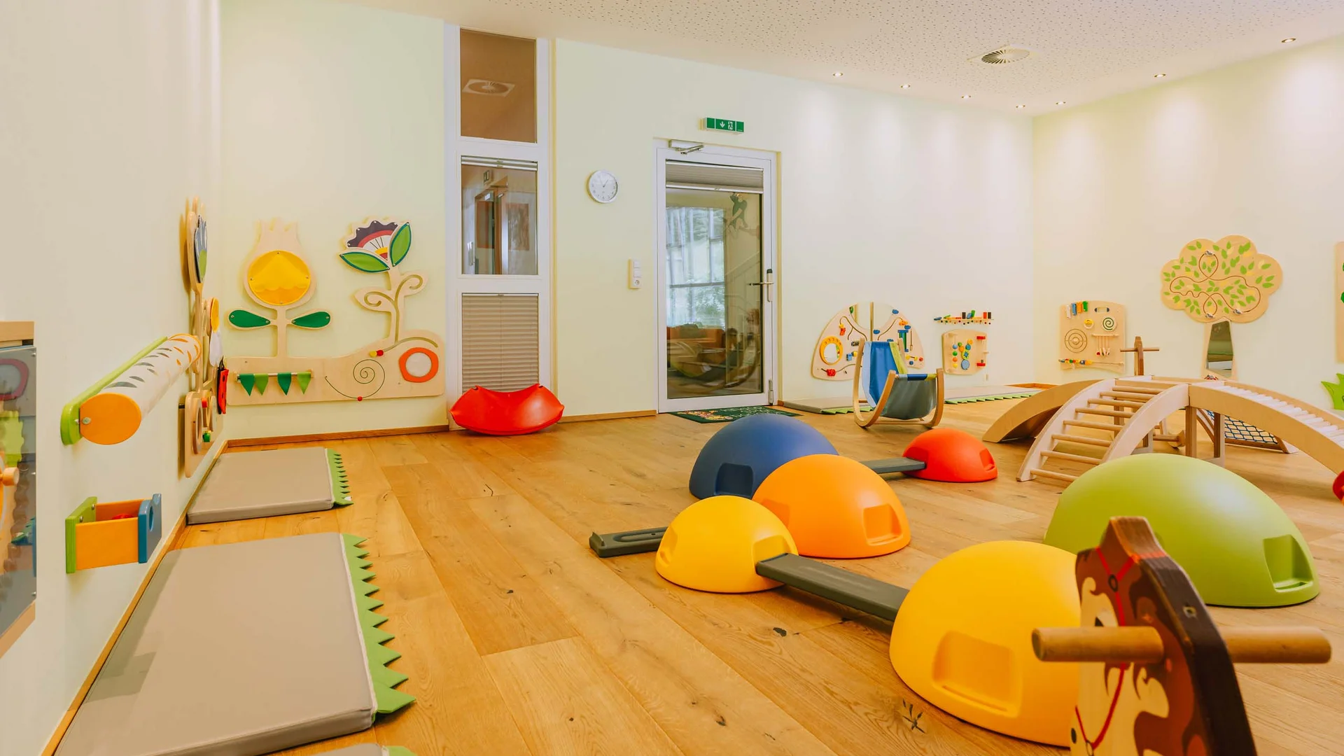 Urlaub im Hotel mit Indoorspielplatz Kinderspielzimmer mit bunten Spielgeräten und Holzspielzeug an der Wand