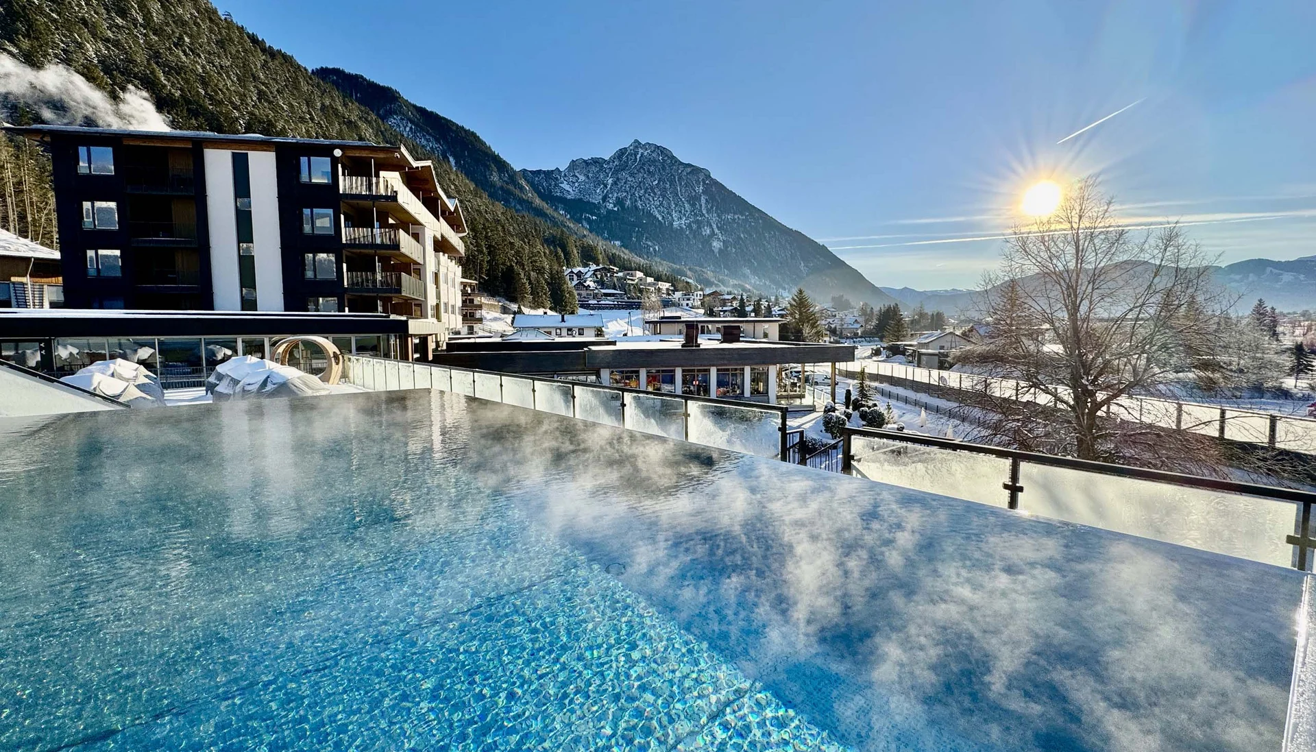 Urlaub im Familienresort in Österreich Verdampfender Außenpool mit Berg- und Sonnensicht im Winter