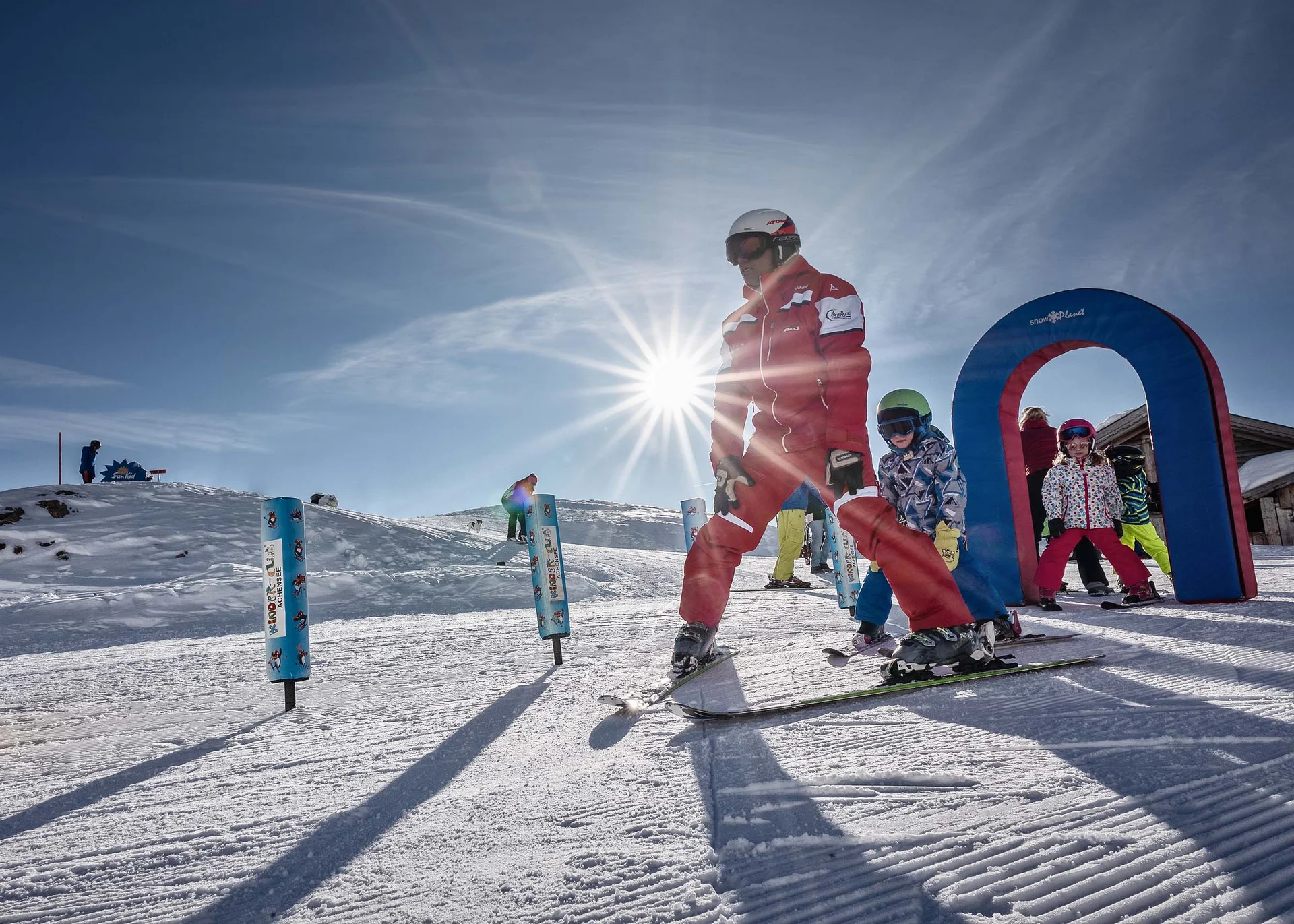 Stammgast werden und Buchau-Taler sammeln Skilehrer mit Kindern beim Skikurs im Schnee an einem sonnigen Tag