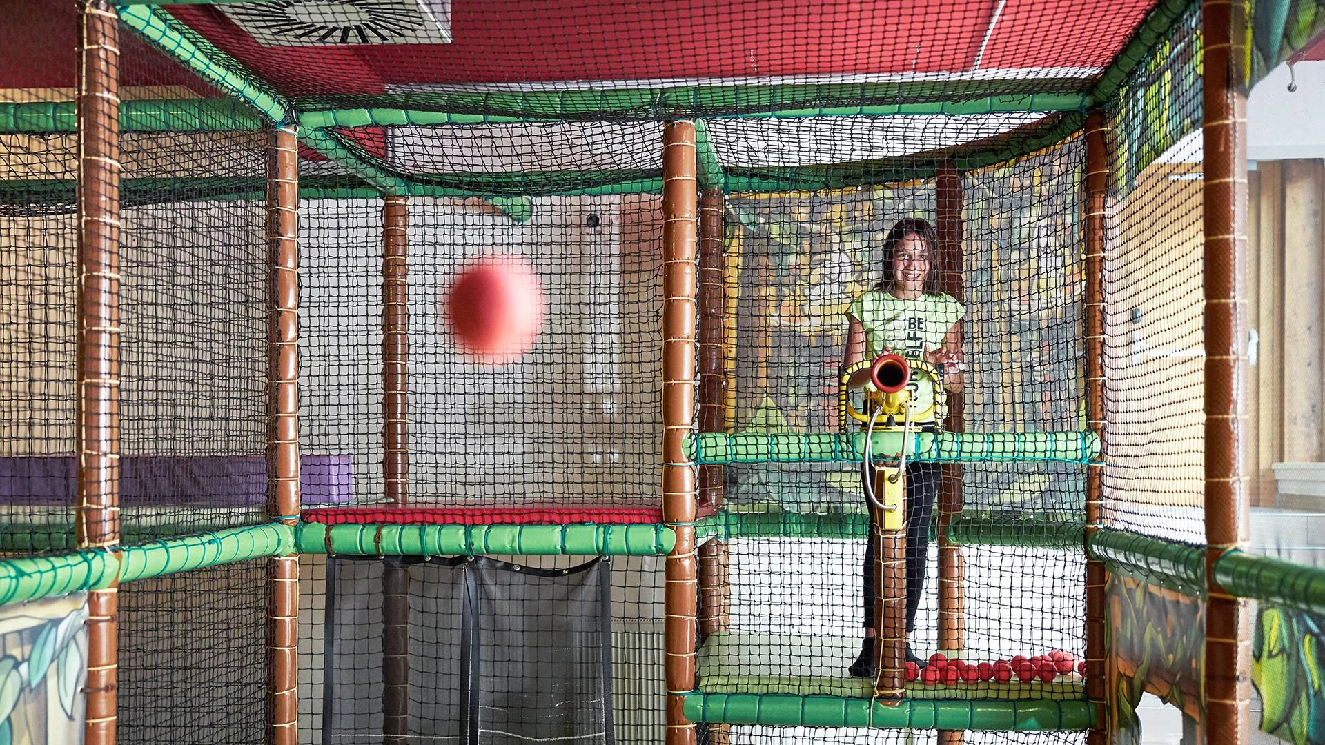 Urlaub im Hotel mit Indoorspielplatz Mädchen spielt mit Bällen in einem Indoor-Spielplatz mit Netzwänden