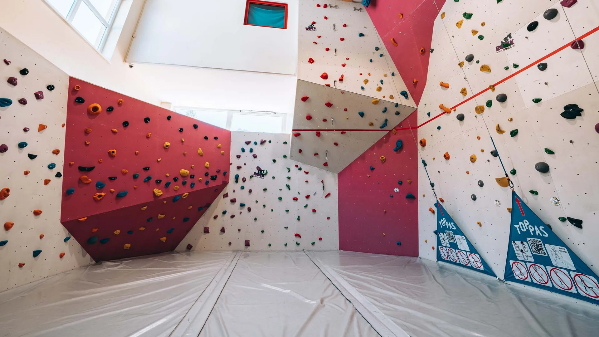 Urlaub im Hotel mit Indoorspielplatz Innenansicht einer Kletterhalle mit bunten Griffen und Matten am Boden