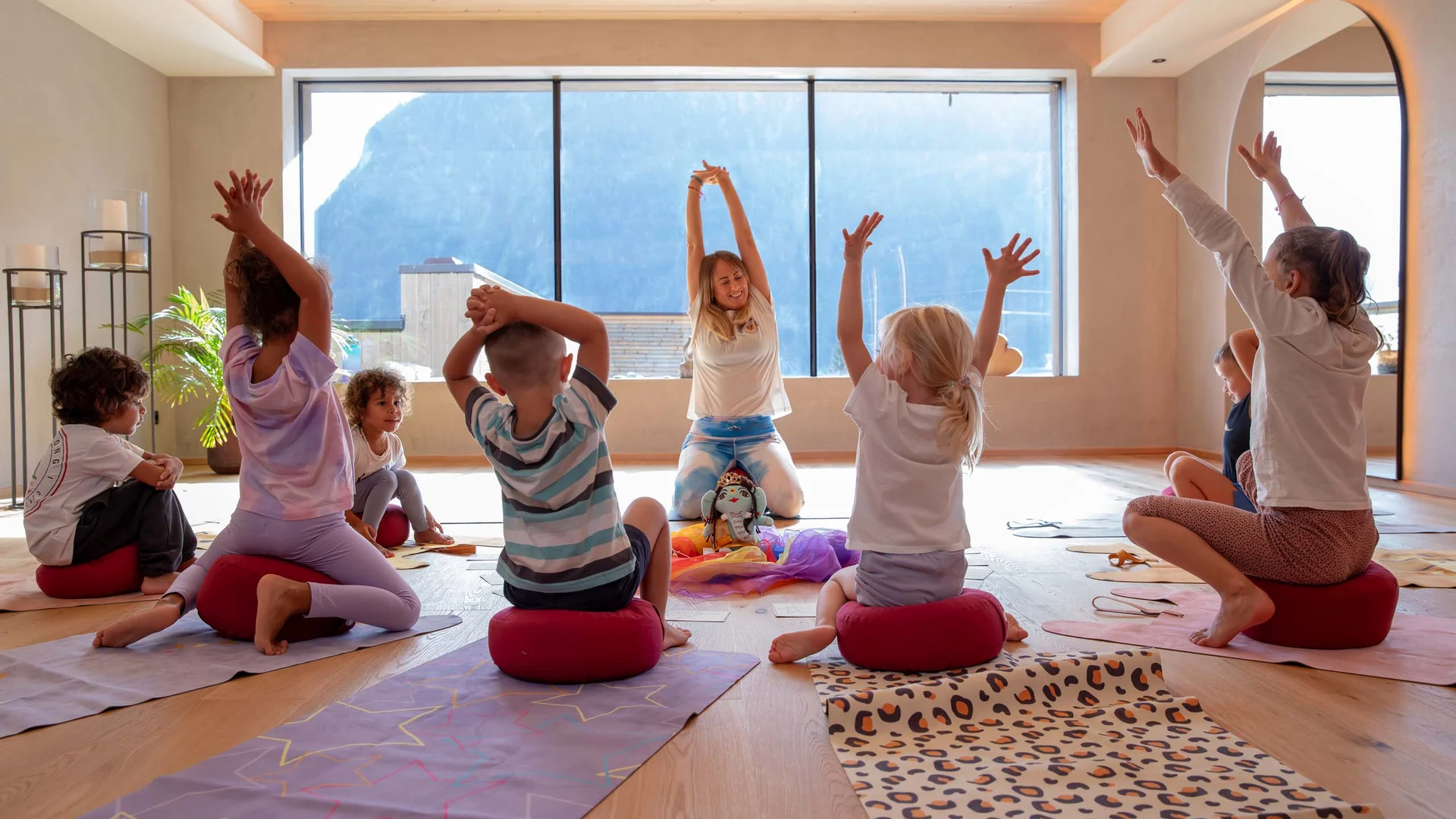 Ihr Hotel mit Kinderbetreuung in Tirol Kinder machen Yoga-Übungen in einem hellen Raum mit Bergblick