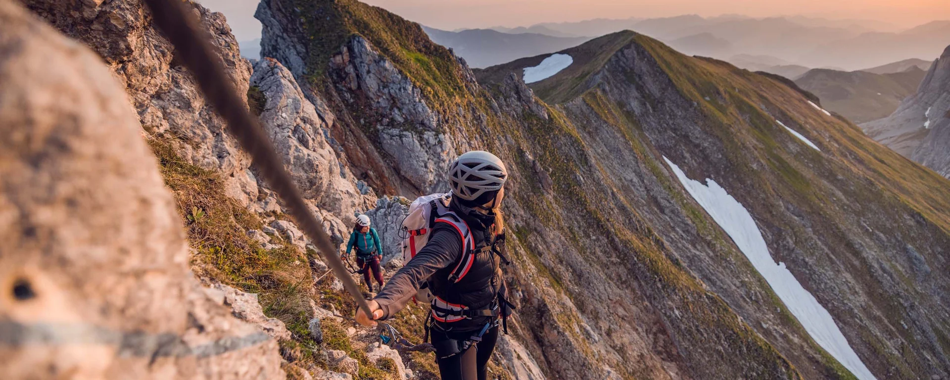 Action im Hotel mit Kletterhalle Kletterer sichert sich am Berggrat mit Seil bei Sonnenuntergang
