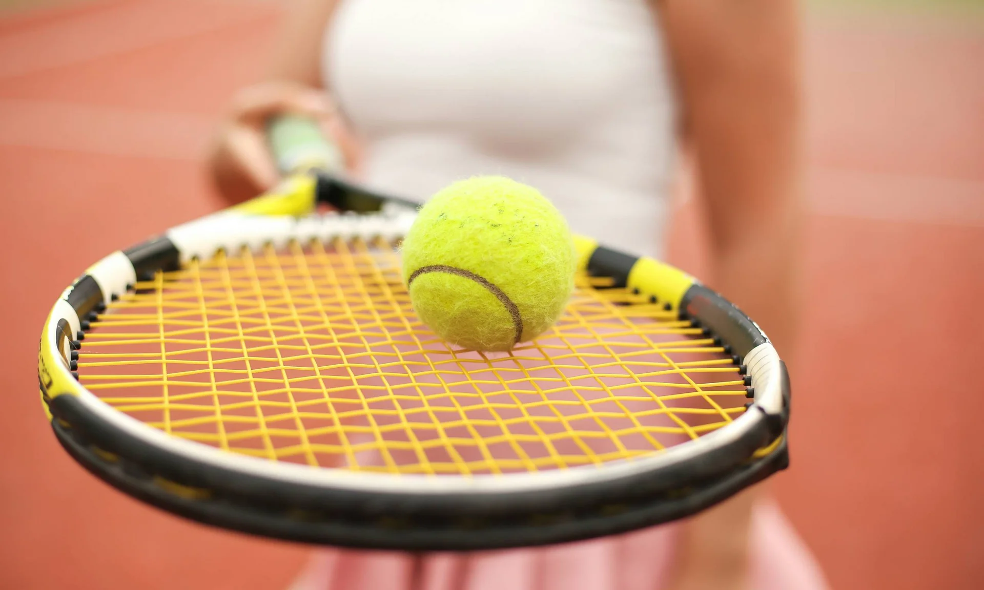 Your unforgettable active lakeside holiday in Austria Tennis ball on tennis racket on red tennis court