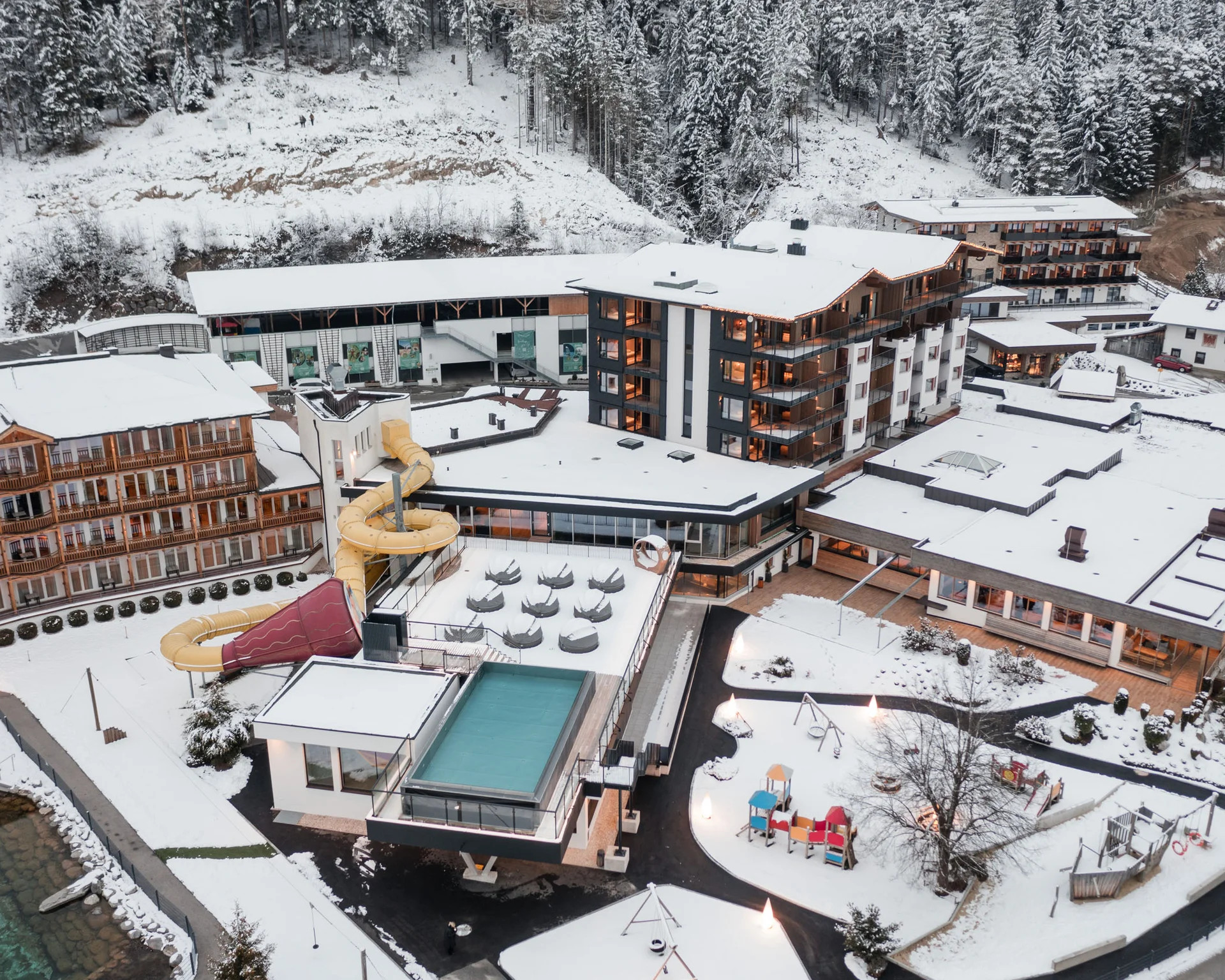 Familienzeit im Kinderhotel Buchau am Achensee Vogelperspektive auf ein schneebedecktes Hotel mit Wasserrutsche im Winter