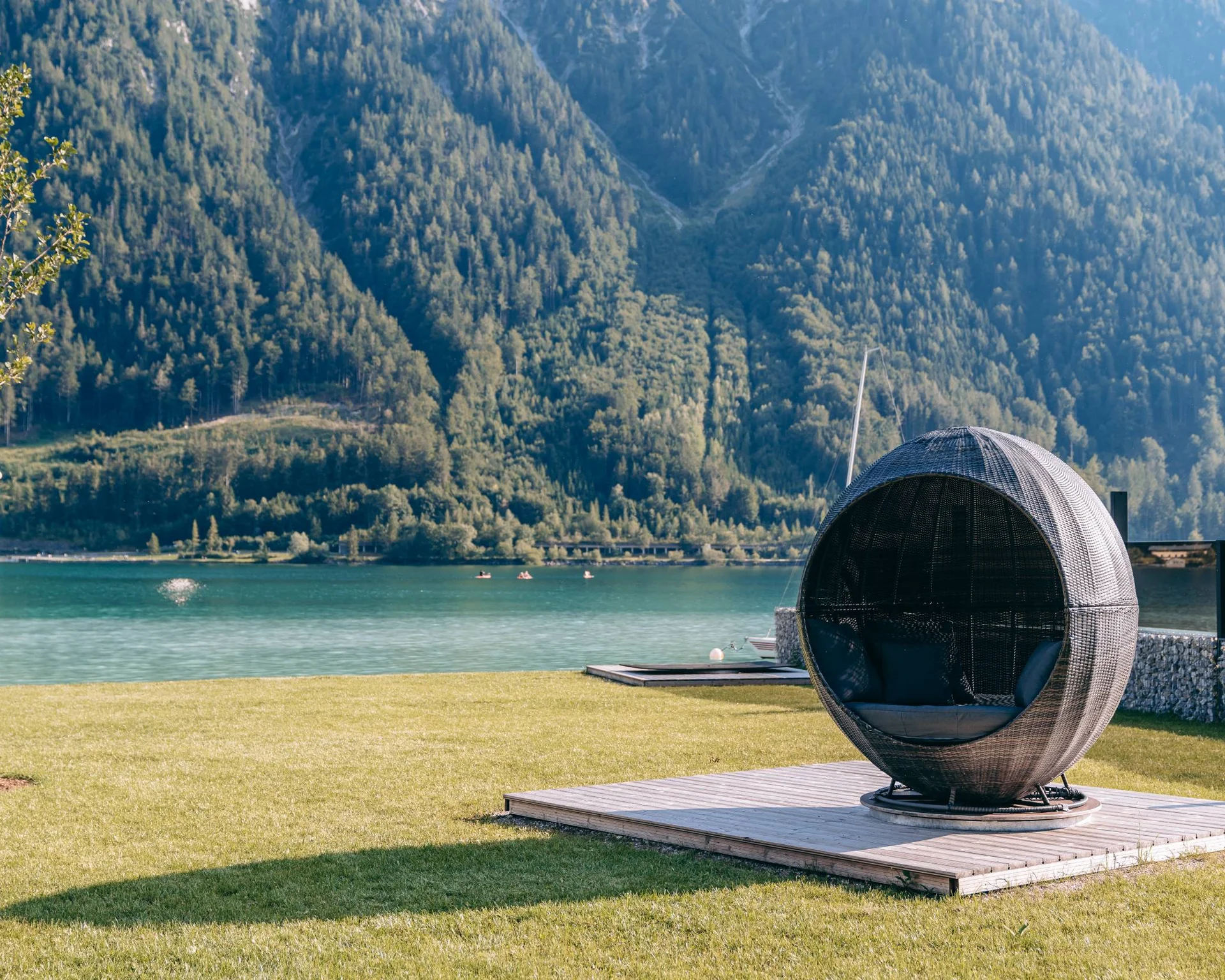 Wassersport auf dem See in Österreich Rundes Loungesessel auf einer Wiese mit Berg- und Seeblick im Hintergrund