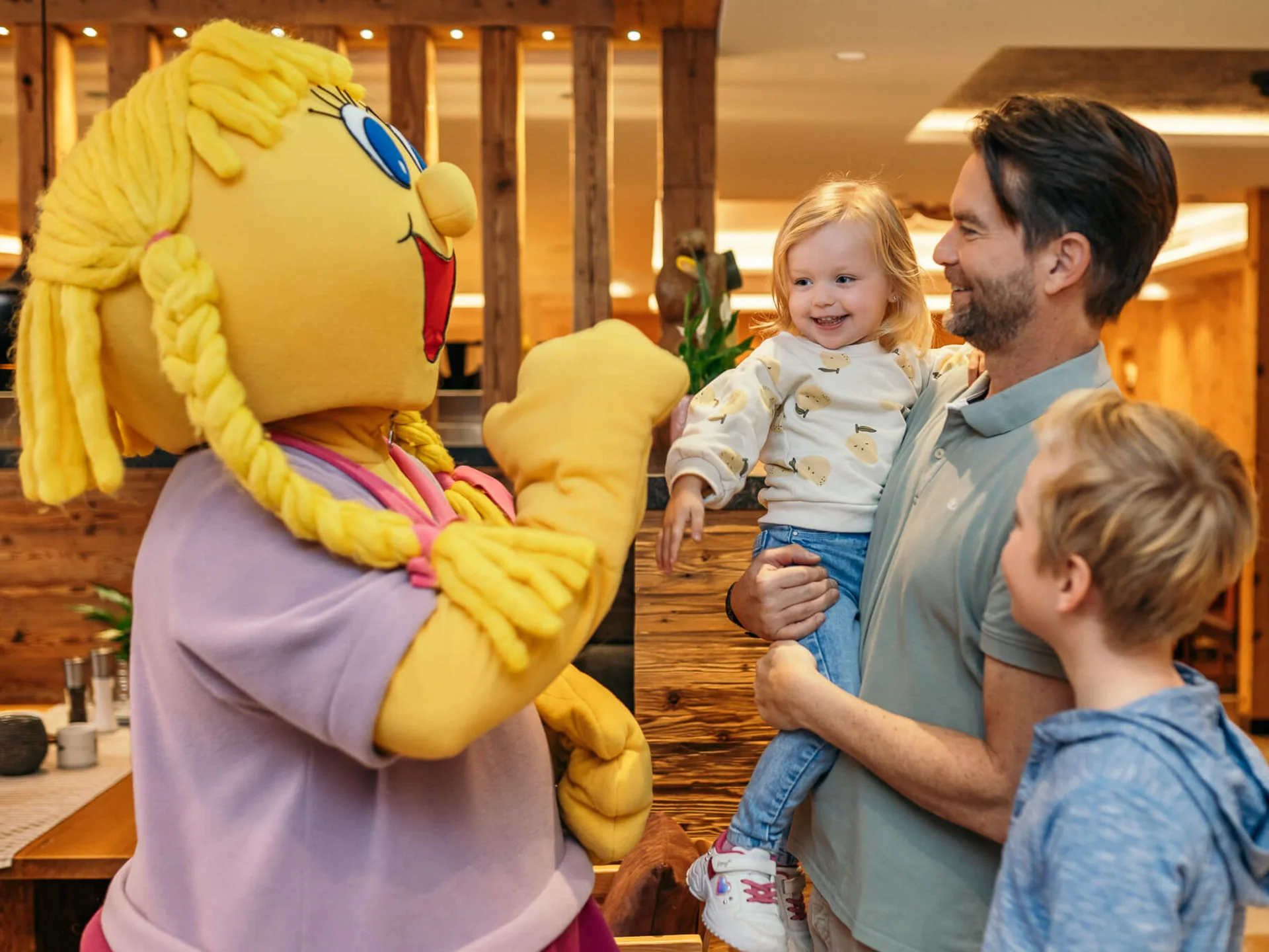 Stammgast werden und Buchau-Taler sammeln Kind lacht, während es mit einem gelben Maskottchen im Restaurant interagiert