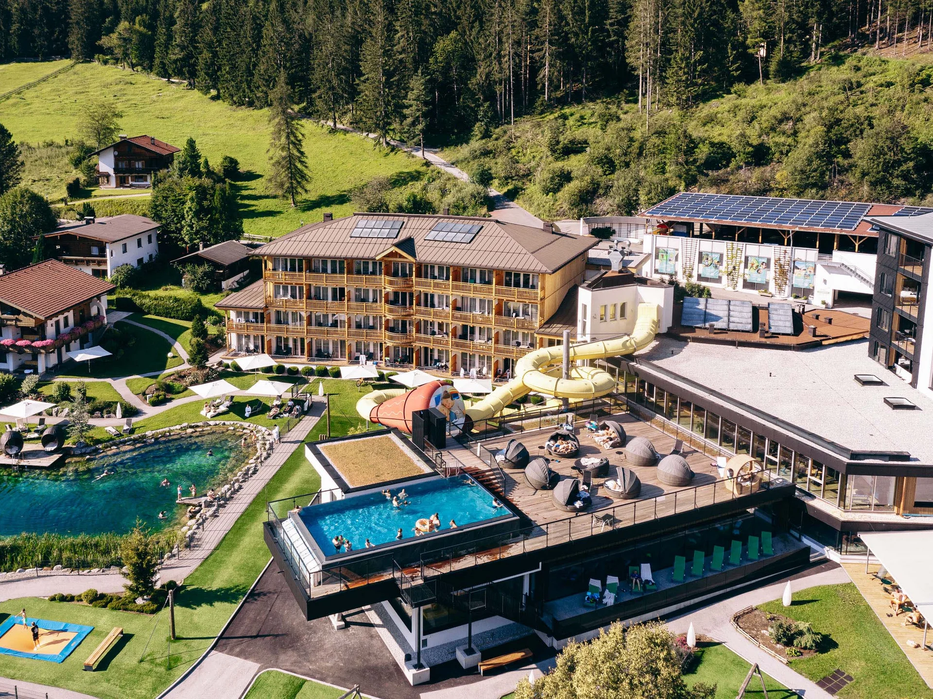 Ab ins Wellnesshotel in Tirol, in den Infinitypool! Hotelanlage mit Schwimmbad, Wasserrutsche und Sauna im Waldgebiet