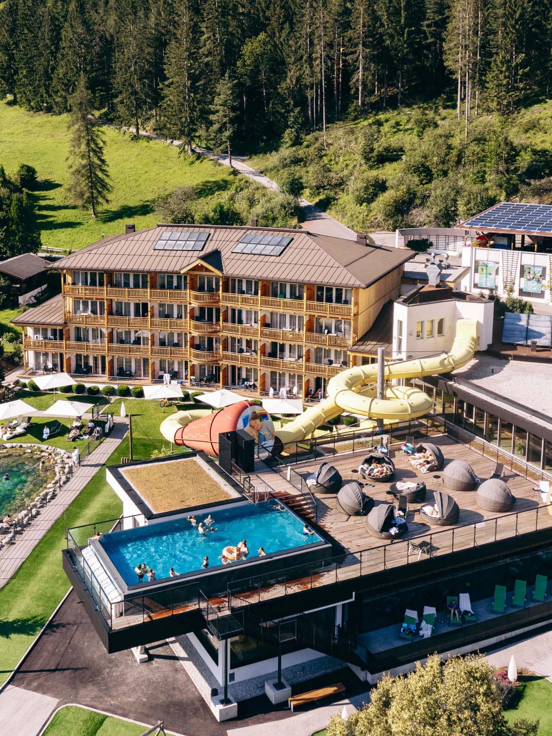Urlaub im Familienresort in Österreich Hotelanlage mit Schwimmbad, Wasserrutsche und Sauna im Waldgebiet