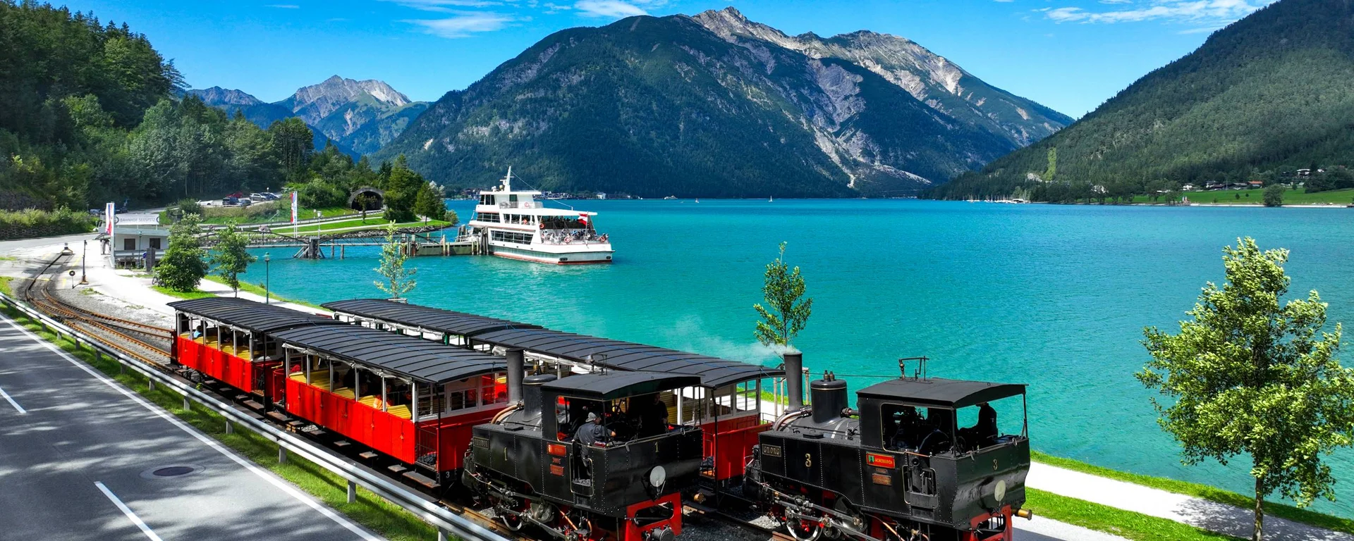 Sehenswertes rund um Eben am Achensee Dampflokomotive und Passagierwagen am See mit Bergen im Hintergrund