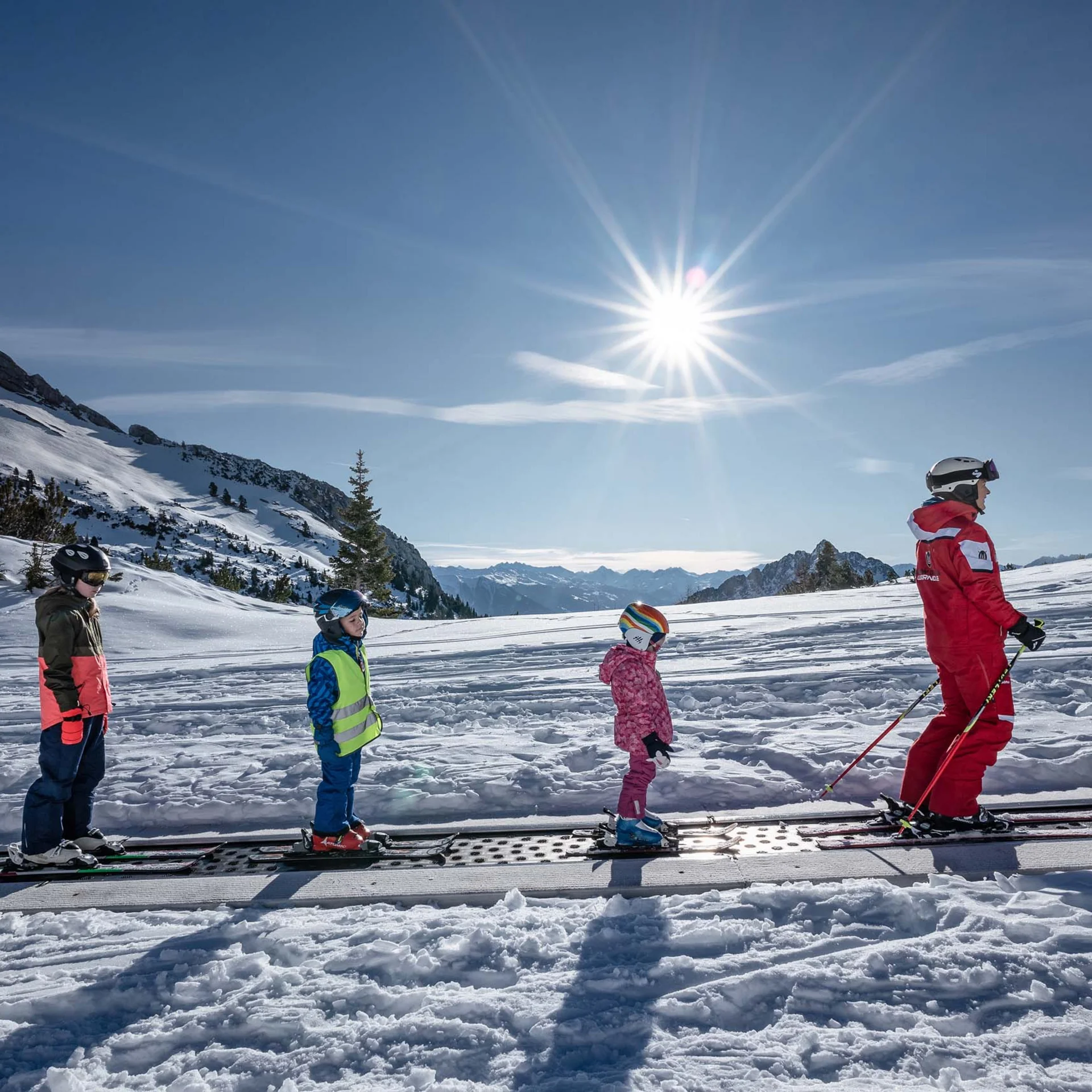 Welcome to our family hotel at Lake Achensee. Children and ski instructor on a conveyor belt in a sunny snowy ski area