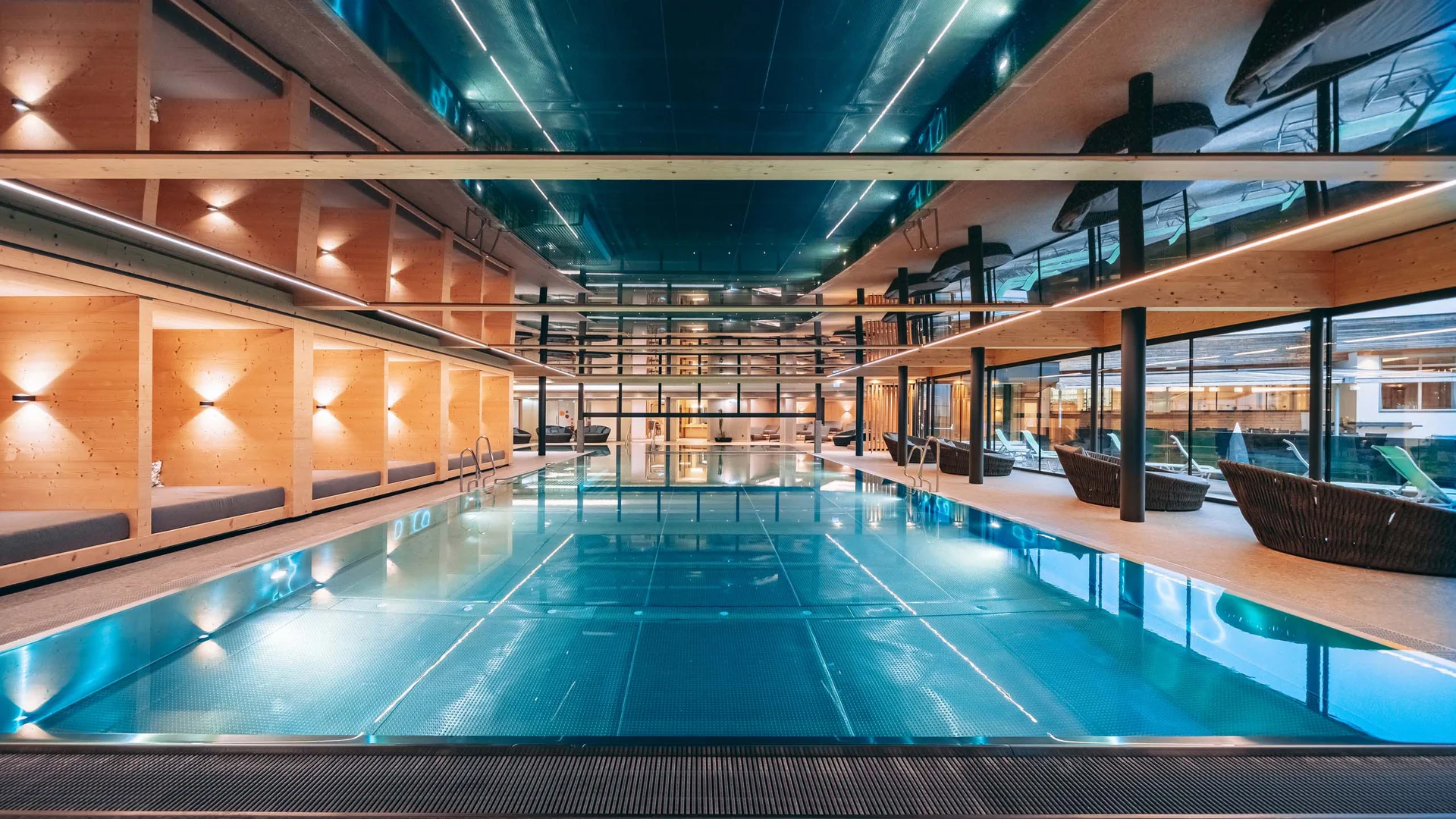 Ihr Familienhotel in Österreich mit All-inclusive-Angebot Moderner Innenpool mit Holzwänden und Liegestühlen