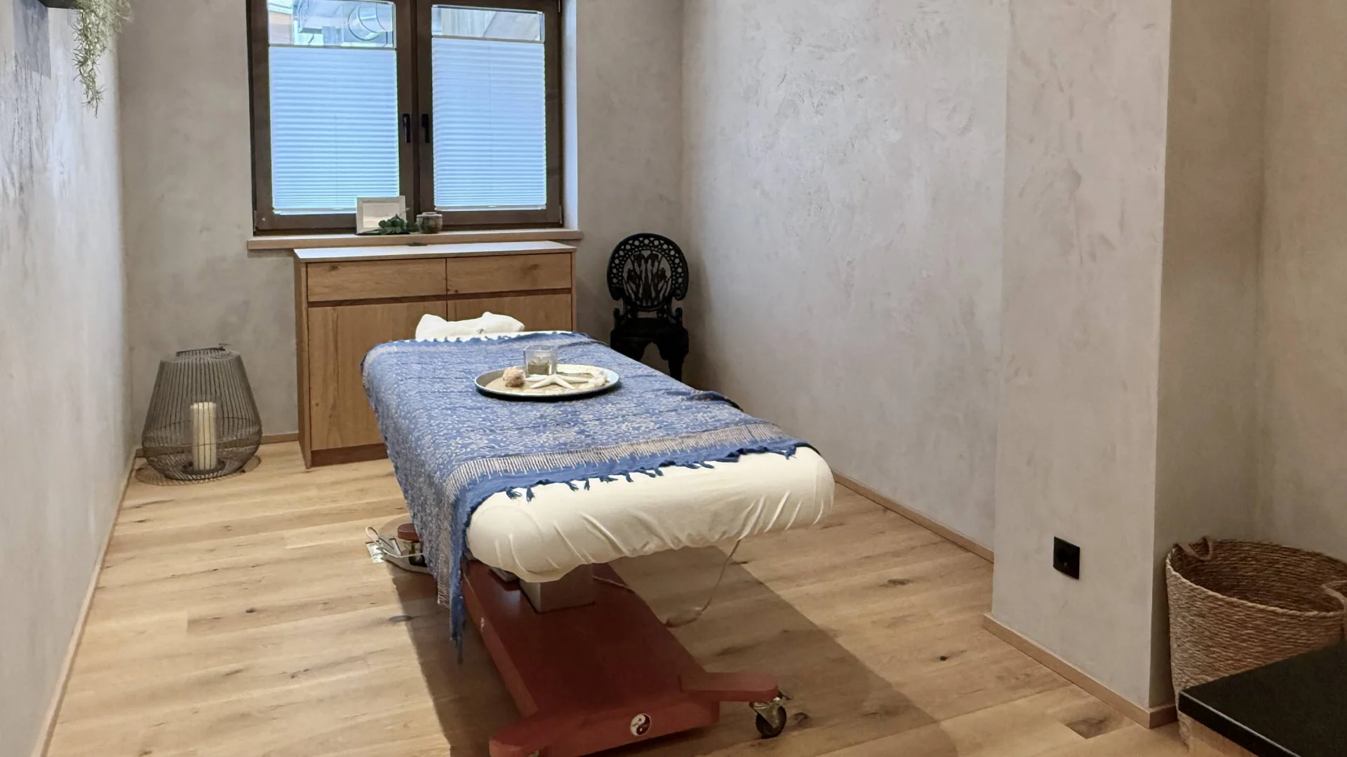 Urlaub im Wellnesshotel mit Kindern in Tirol Sanfter Massageraum mit Behandlungsbett, Holzmöbeln und entspannender Dekoration