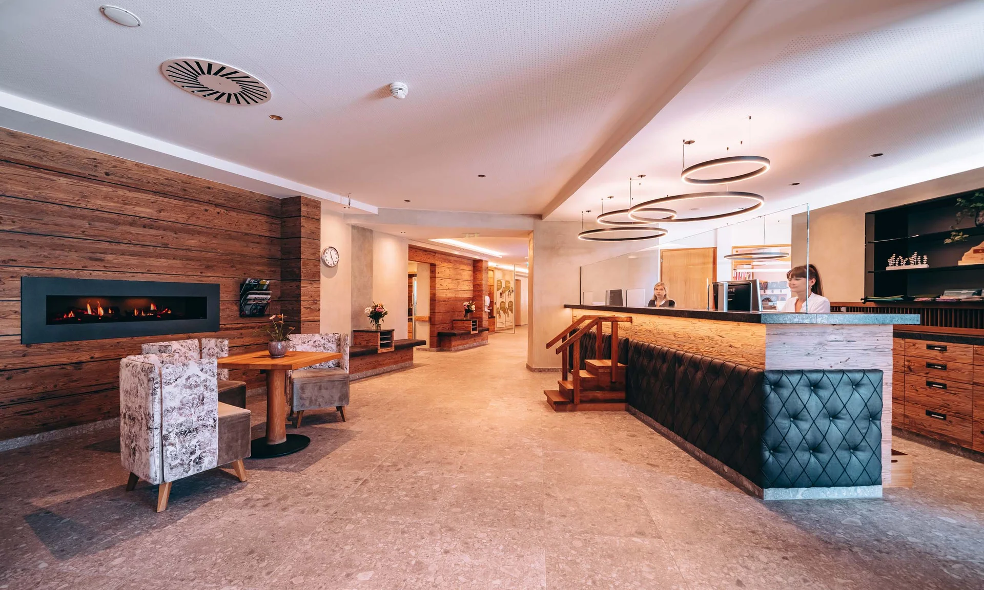 Urlaub im Familienresort in Österreich Moderner Hotellobby mit Rezeption, Sitzbereich und Kamin an Holzwand