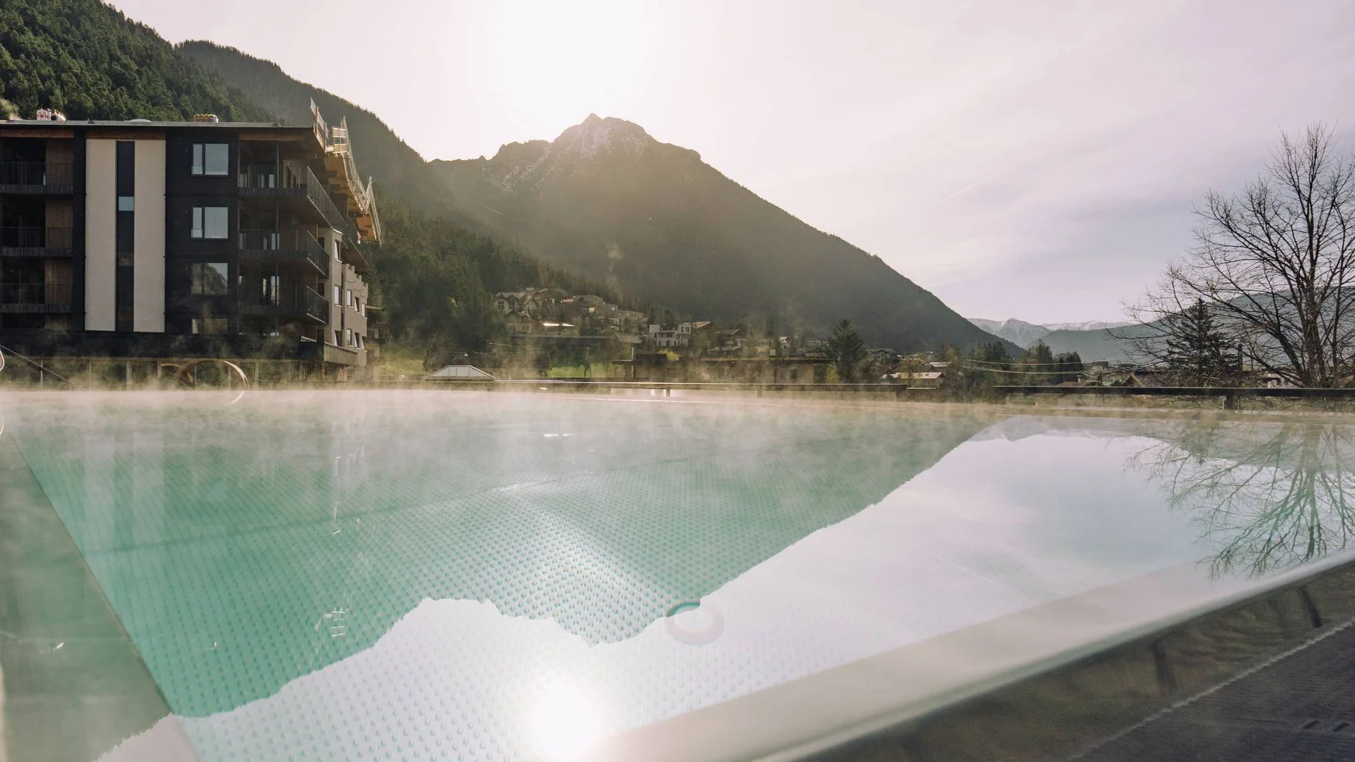 Wasserspaß im Familienhotel in Tirol mit Pool Dampfschwimmbecken mit Bergblick bei Sonnenuntergang