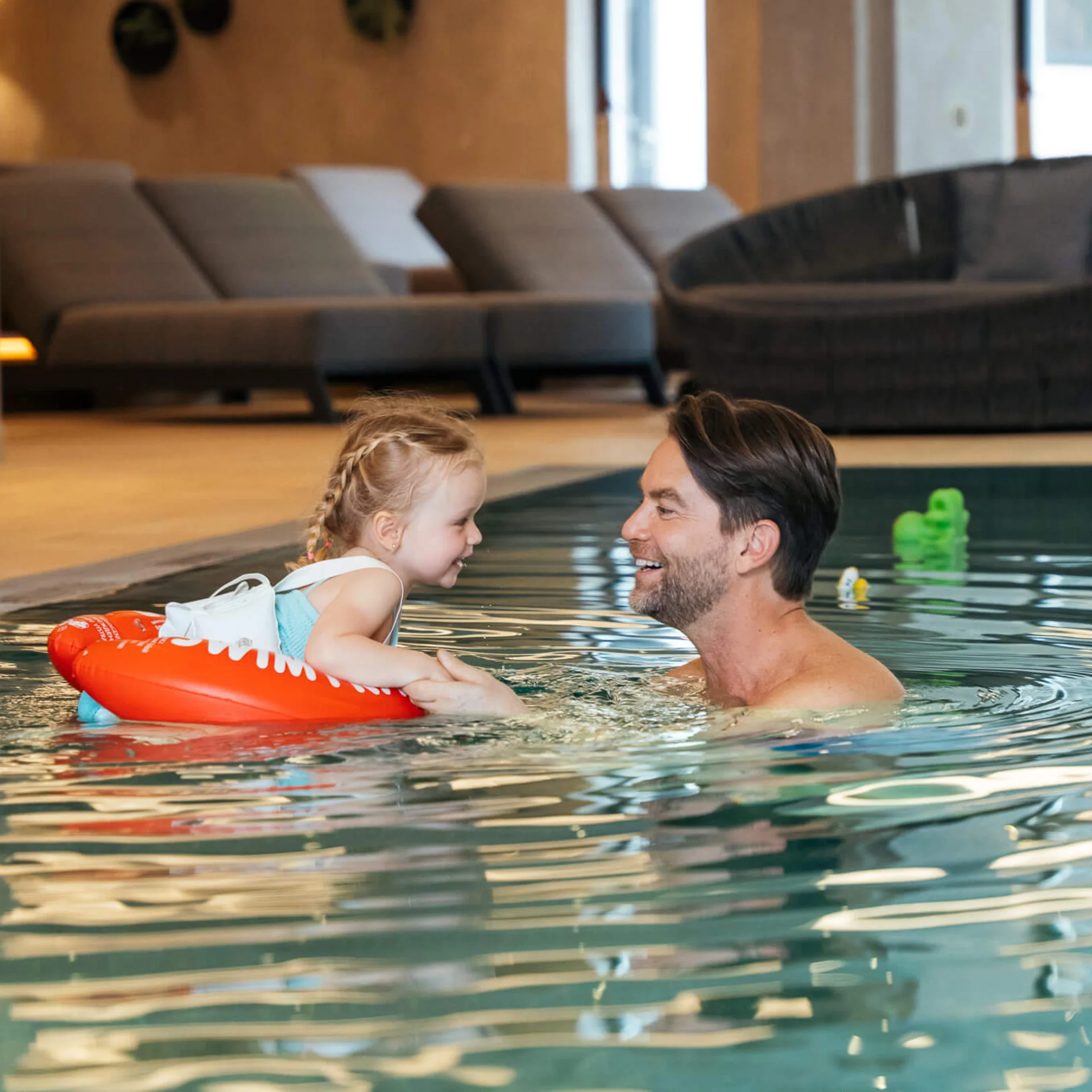Welcome to our family hotel at Lake Achensee. Father and daughter laughing and playing together in indoor swimming pool