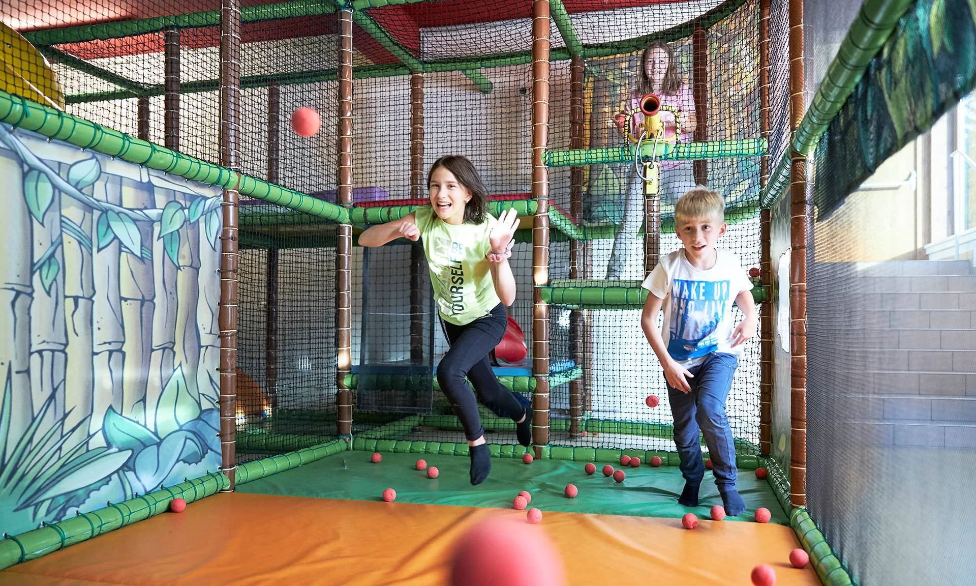 Urlaub im Hotel mit Indoorspielplatz Kinder spielen in einer Indoor-Spielanlage mit roten Schaumstoffbällen