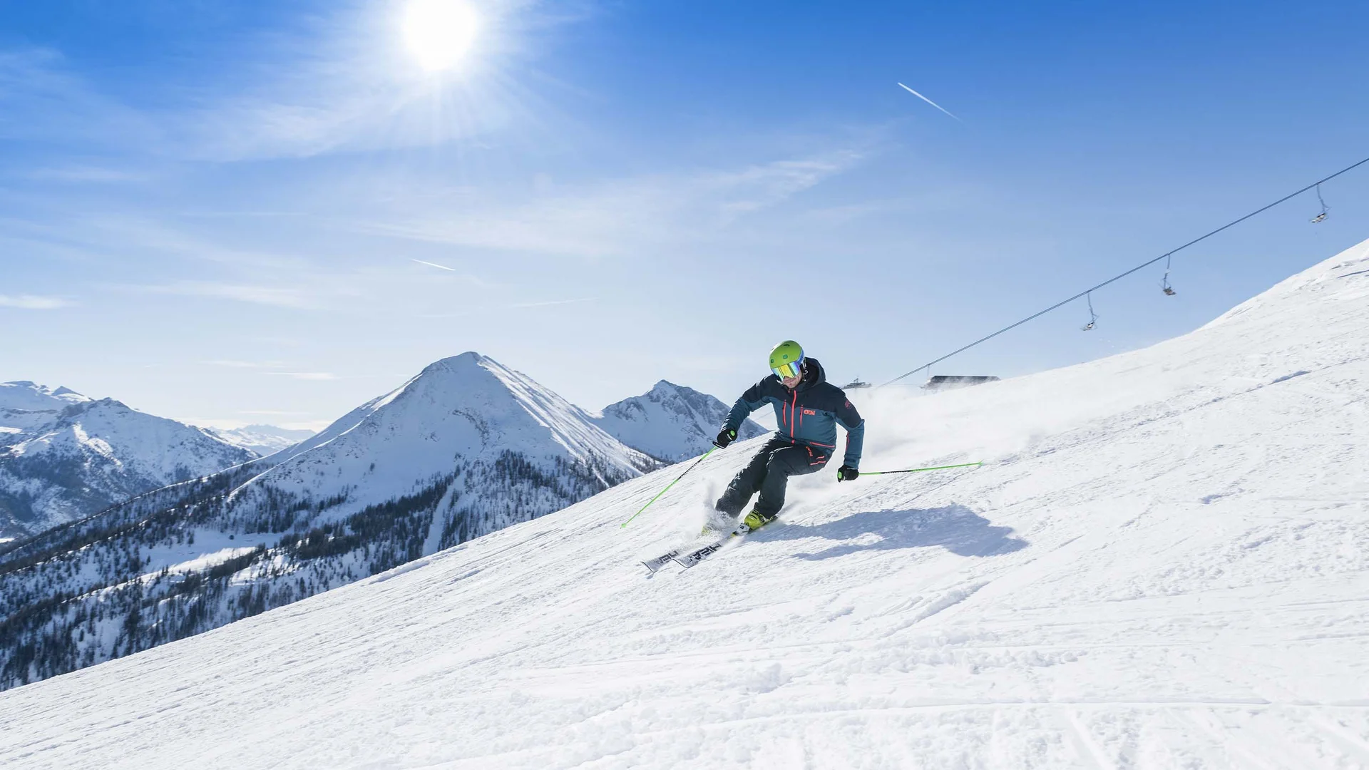 Willkommen im Familienhotel Buchau am Achensee Skifahrer fährt bei sonnigem Wetter den schneebedeckten Berghang hinab