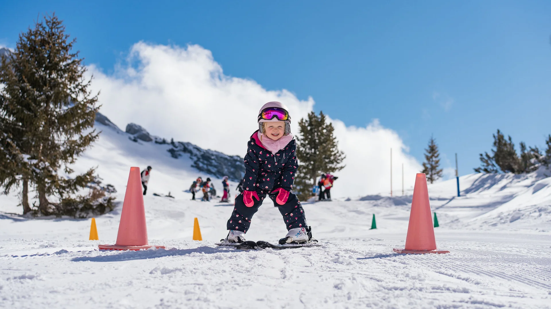 Ihr Familienhotel in Österreich mit All-inclusive-Angebot Kind lernt Skifahren zwischen Hütchen auf schneebedeckter Piste an sonnigem Tag