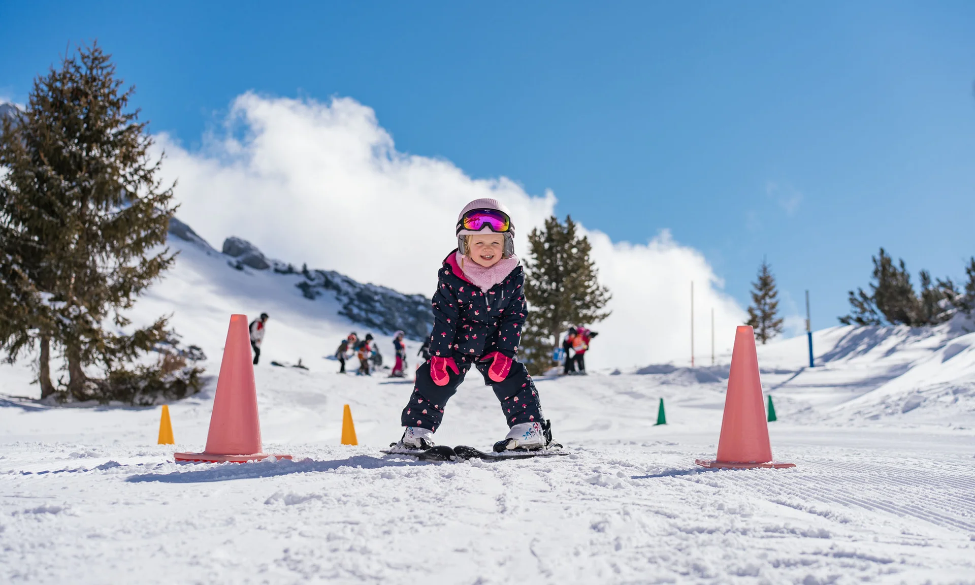 Familienurlaub mit Baby und Kleinkind im Buchau Kind lernt Skifahren zwischen Hütchen auf schneebedeckter Piste an sonnigem Tag
