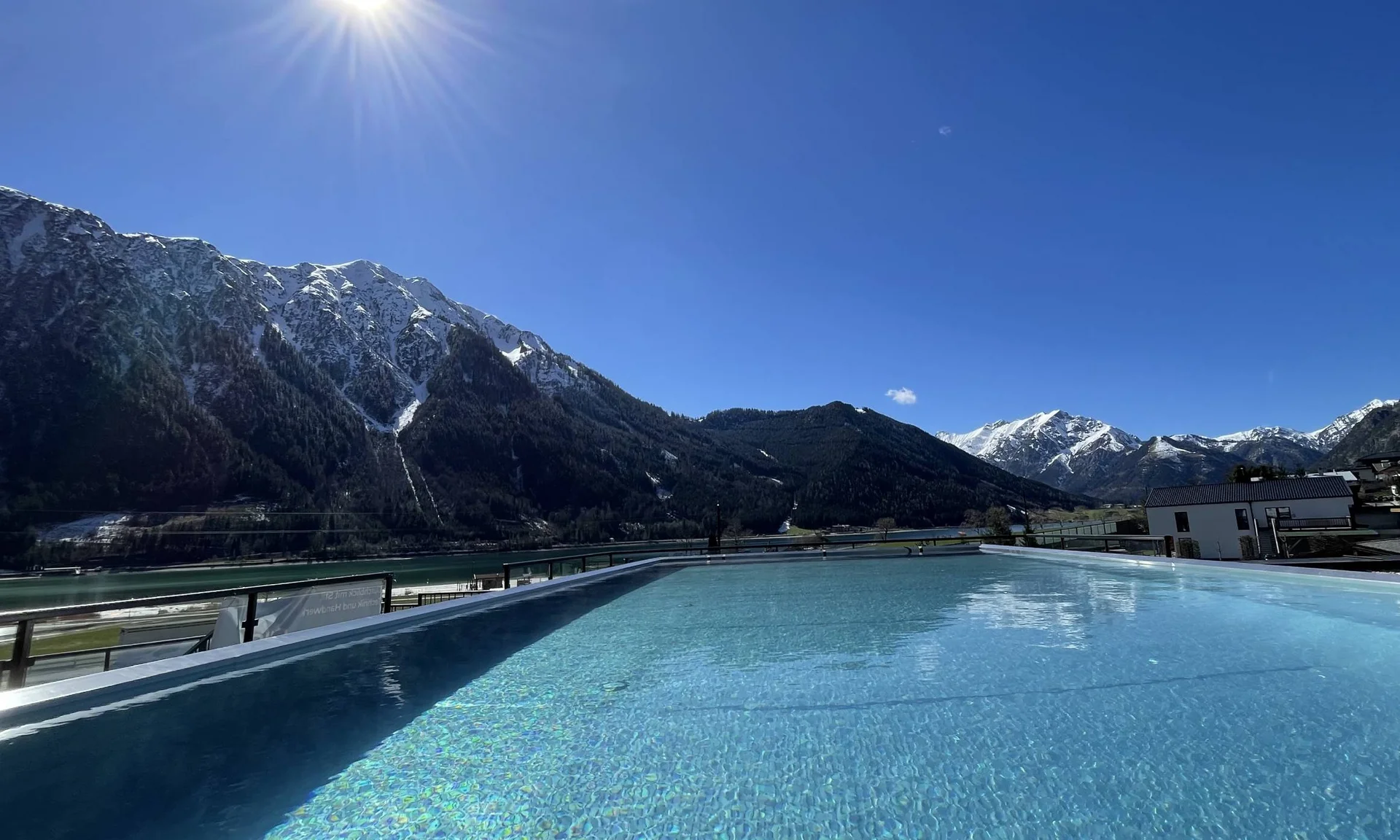 Wir lassen Bilder sprechen. Blick auf einen Pool mit Berglandschaft und Sonnenschein bei klarem Himmel