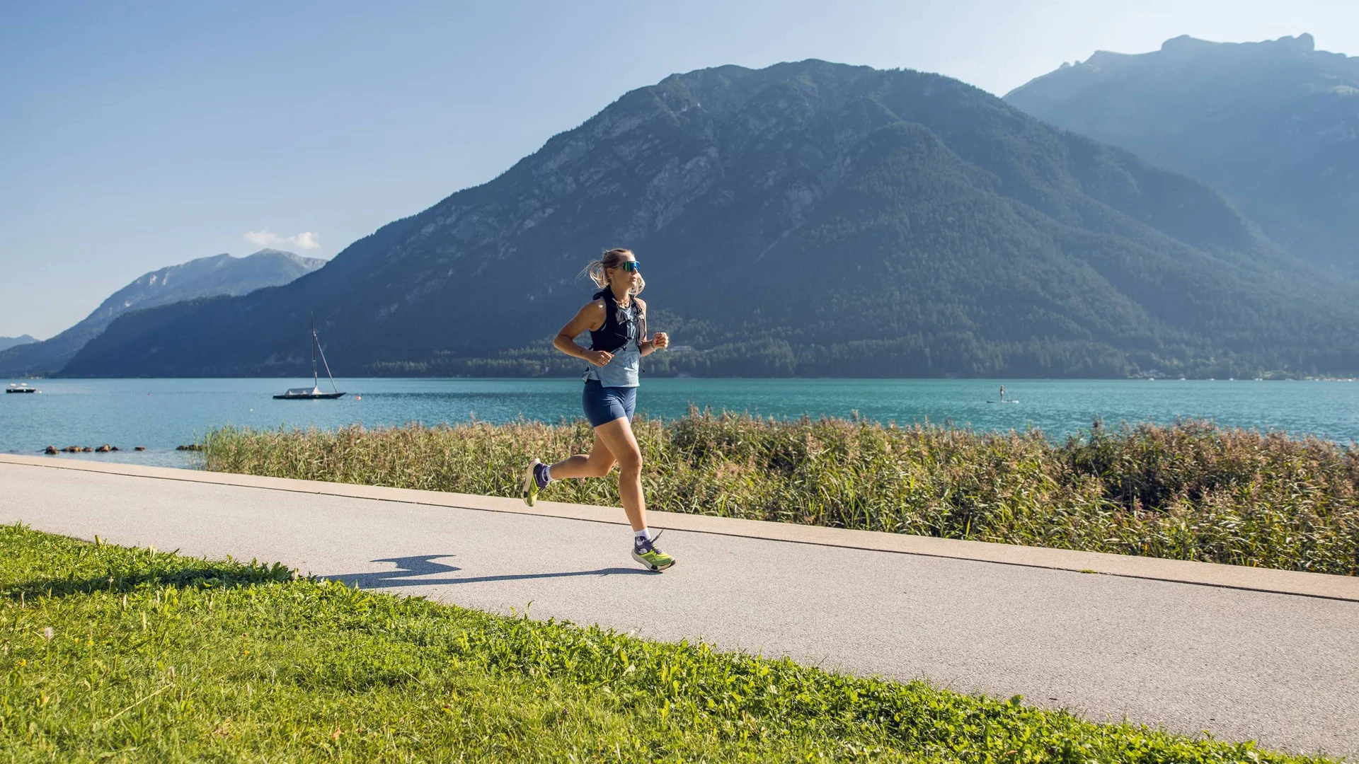 Your unforgettable active lakeside holiday in Austria Woman running on path by lake with mountains in background on clear day
