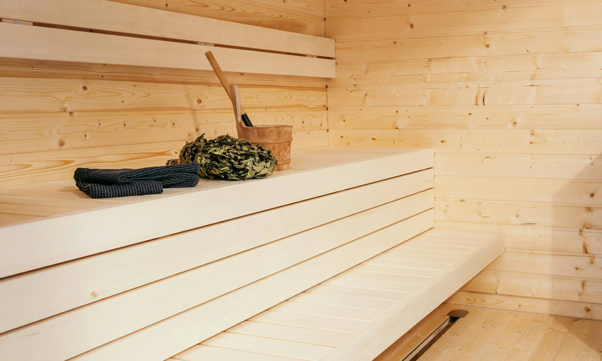 Urlaub im Wellnesshotel mit Kindern in Tirol Moderner Saunaraum mit Holzbänken und Saunaofen mit Saunazubehör