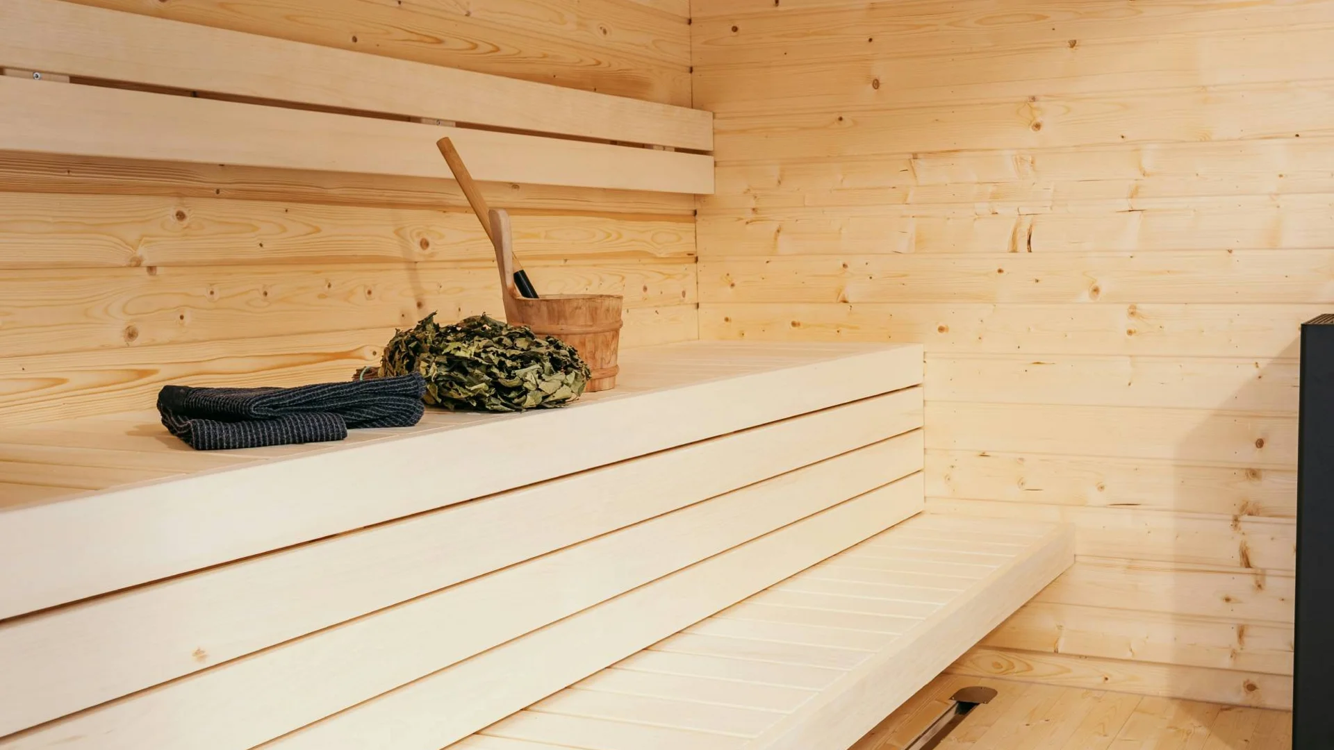 Entspannung im Hotel mit Sauna in Österreich Moderner Saunaraum mit Holzbänken und Saunaofen mit Saunazubehör