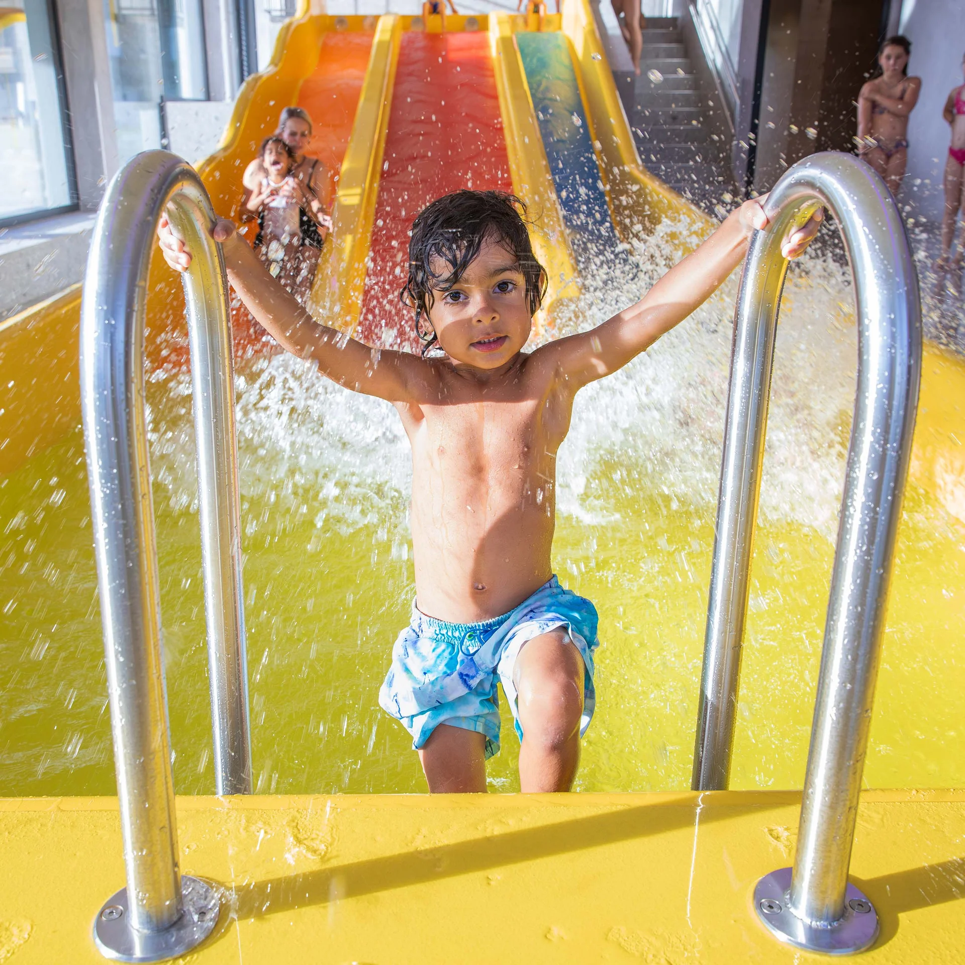 Familienzeit im Kinderhotel Buchau am Achensee Kind steigt nach Rutsche aus Wasserbecken in einem Hallenbad