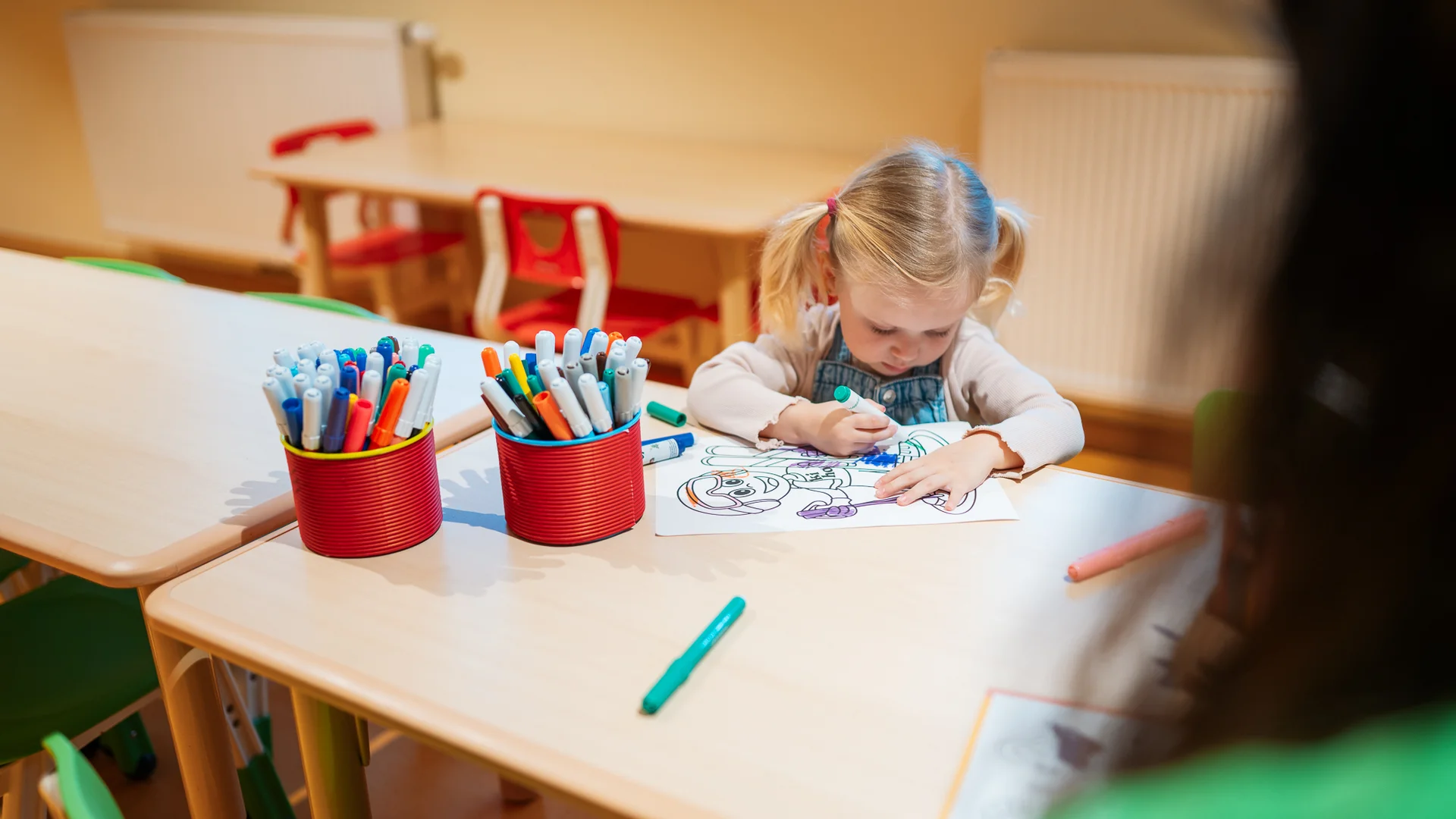 Freizeitkurse für Ihre Kids und Teenies Kleines Mädchen malt mit Filzstift an einem Tisch in einem Klassenzimmer