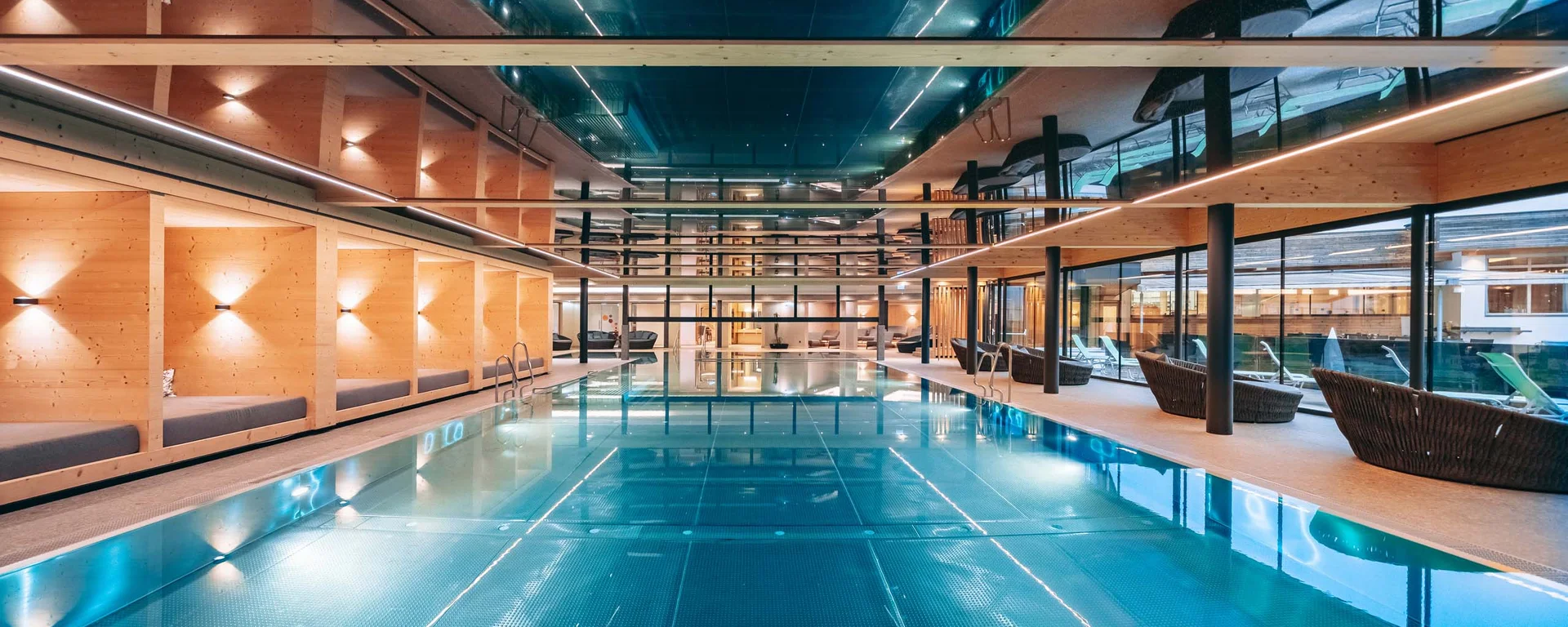 Ab ins Wellnesshotel in Tirol, in den Infinitypool! Moderner Innenpool mit Holzvertäfelung und Sitzbereichen