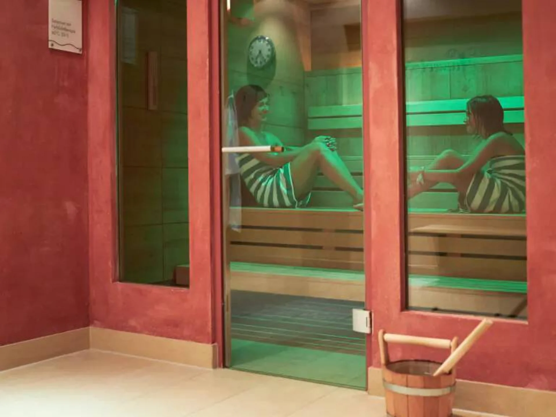 Entspannung im Hotel mit Sauna in Österreich Zwei Frauen entspannen in einer Sauna mit grüner Beleuchtung